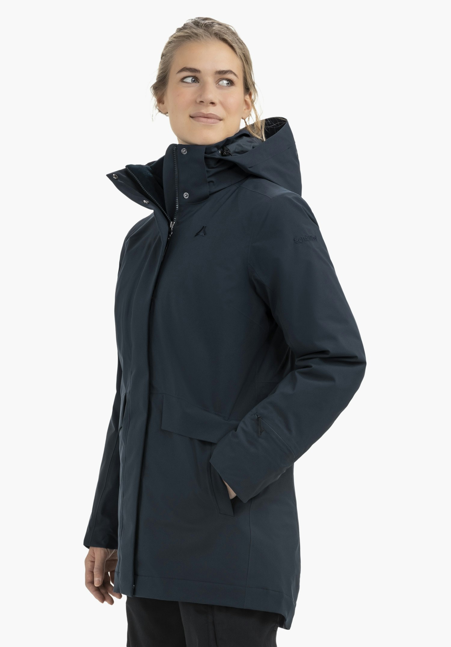 3in1 Parka Style Borkol WMS donkerblauwe jas gedragen door een vrouw die zijwaarts kijkt met handen in de zakken; staande pose voor een witte achtergrond. Schöffel-logo zichtbaar; tekst: "Schöffel".