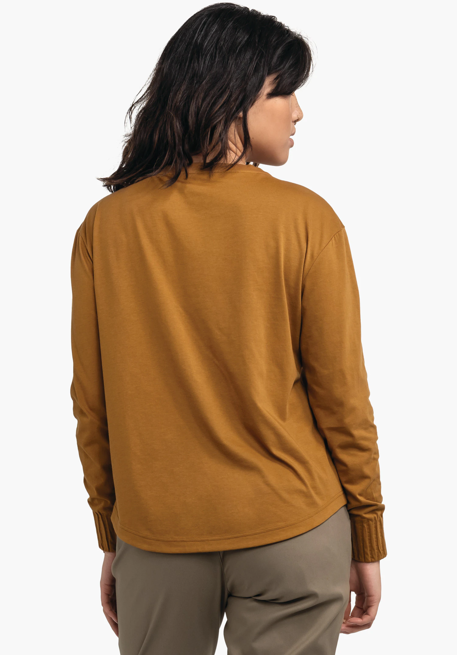 Longsleeve Style Collada WMS haut manches longues jaune foncé, dos au spectateur, tête légèrement tournée; debout devant un fond blanc neutre.