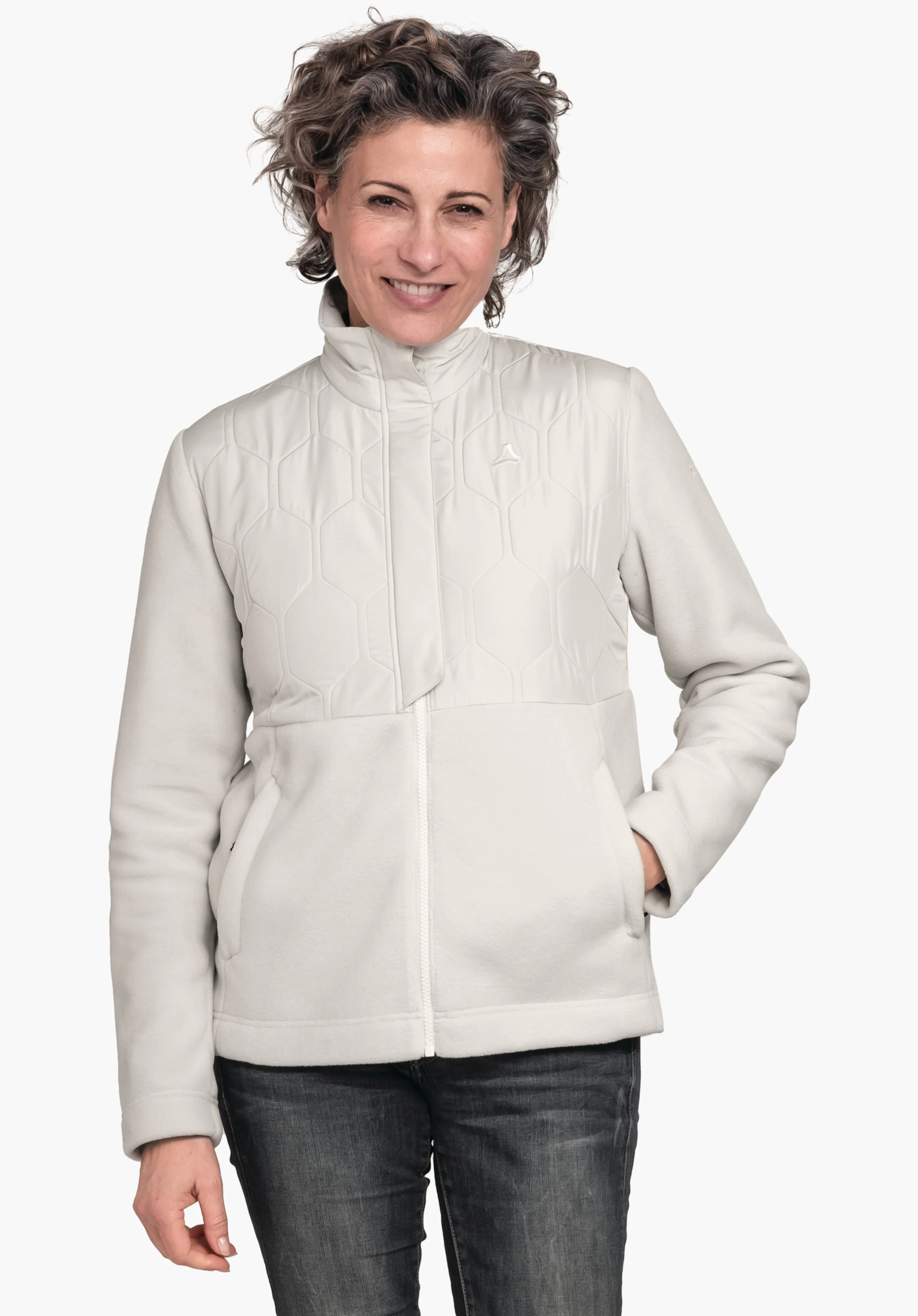 Fleece Jk Style Gregale WMS veste doublée blanc clair avec logo Schöffel; femme la portant, souriante, main droite dans la poche, pose debout devant un fond clair uni, jean bleu foncé.