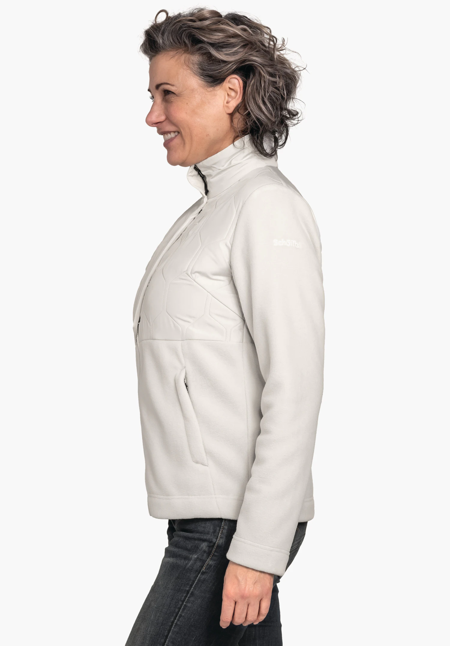 Fleece Jk Style Gregale WMS lichtwitte jas gedragen door een vrouw in profiel die glimlacht; staat zijwaarts voor een lichte achtergrond. Tekst op de mouw: "Schöffel".