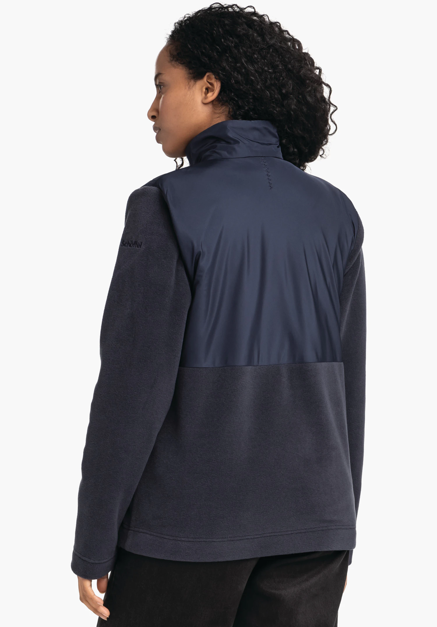 Fleece Jk Style Gregale WMS donkerblauwe jas, gedragen door een persoon die zijwaarts staat met de rug naar de camera en naar links kijkt; hoge kraag, witte studioachtergrond. Tekst op de mouw: schöffel.