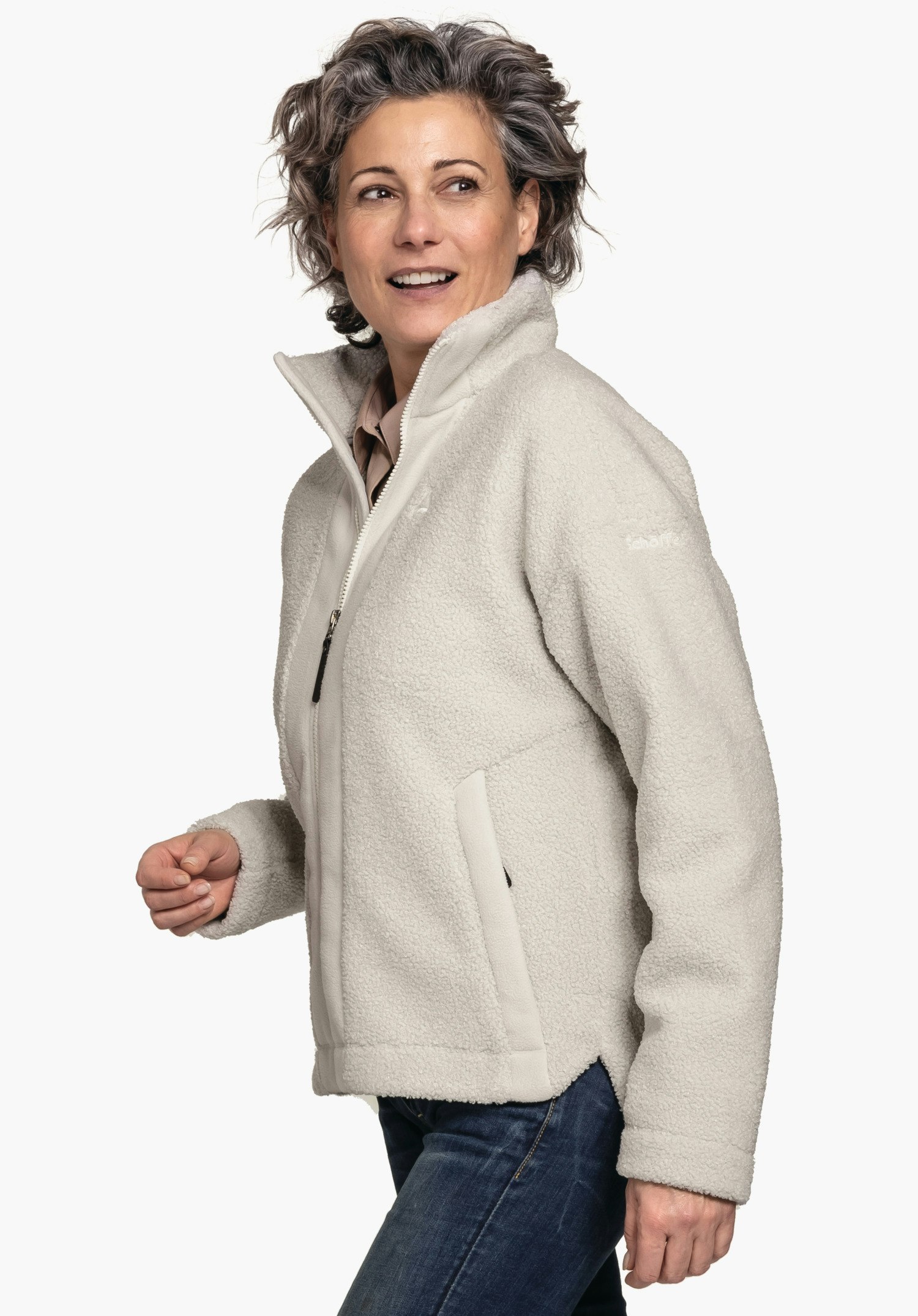 Fleece Jk Style Kalmor WMS light white fleece jacket with Schöffel logo worn by a smiling woman looking side-on and slightly raising her hand; dark blue jeans; neutral white background. Text: "Schöffel".