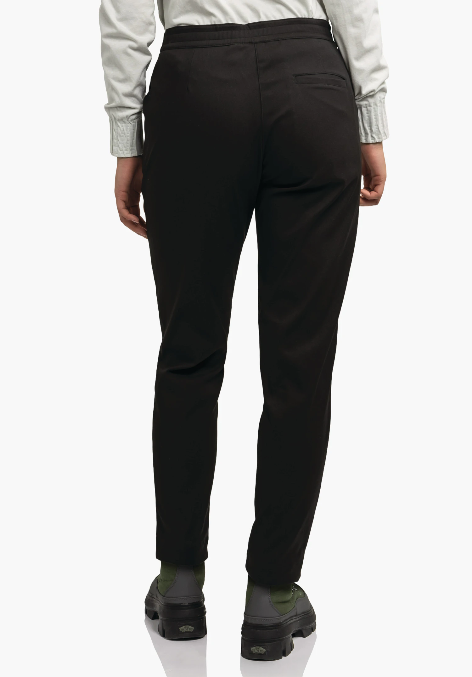 Pants Style Zourga WMS zwarte broek, van achteren gedragen; persoon staat voor een lichte achtergrond en draagt een lichtwit bovenstuk en zwart-groene schoenen.