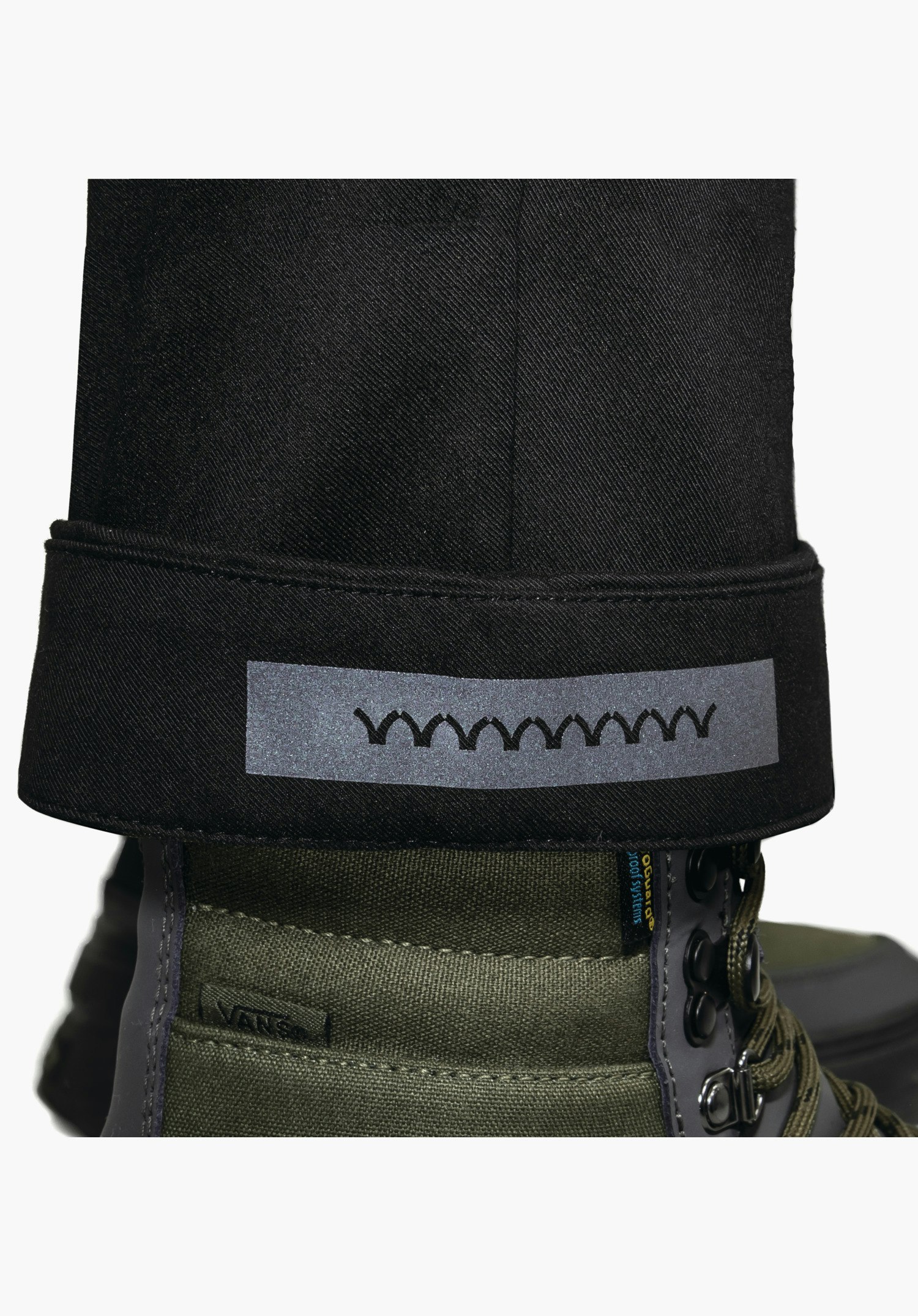 Pants Style Zourga WMS ourlet de pantalon retroussé en noir avec un élément réfléchissant à l'intérieur, gros plan sur fond blanc.