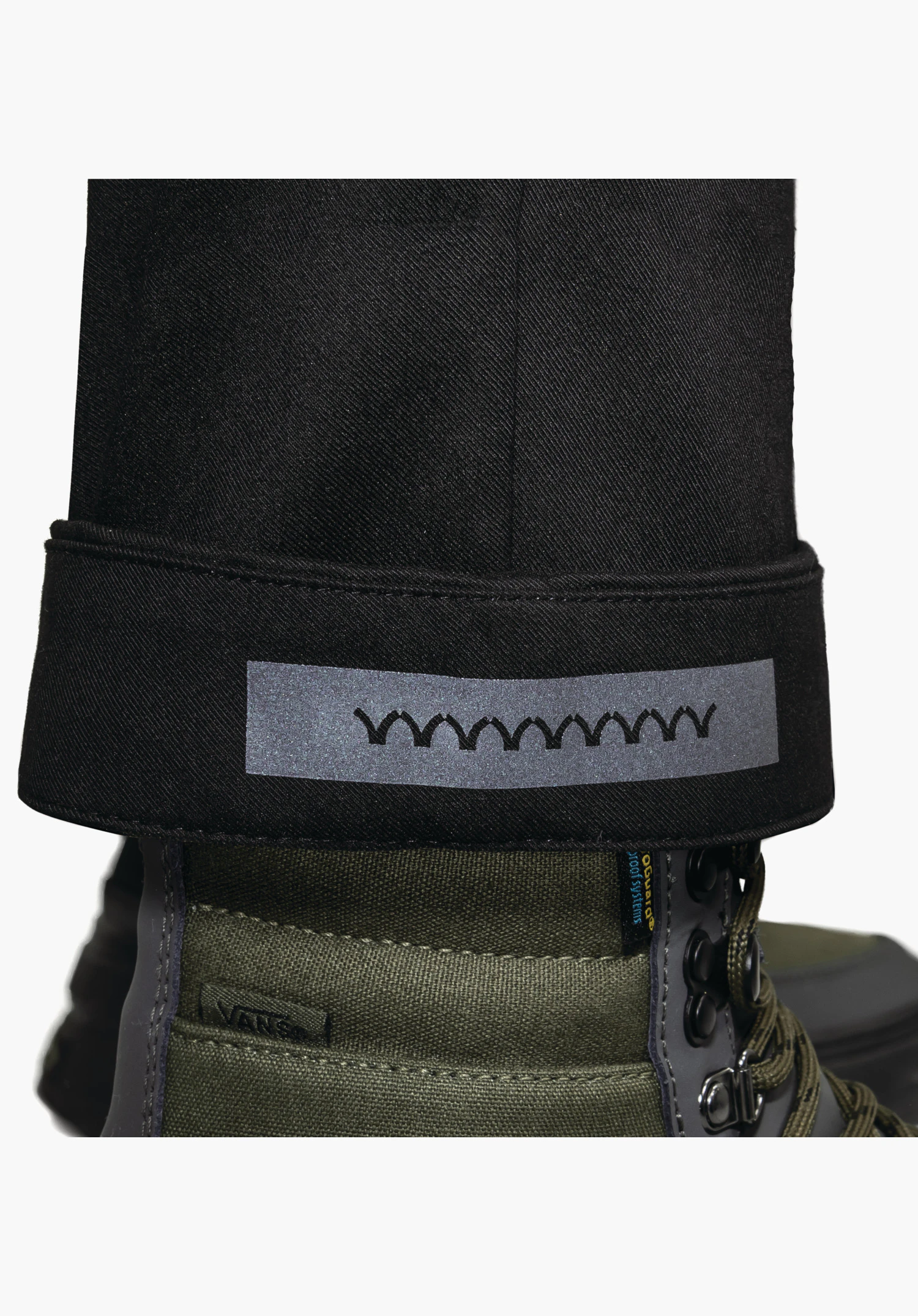 Pants Style Zourga WMS omgeslagen broekspijp in zwart met een reflecterend element aan de binnenkant, close-up tegen een witte achtergrond.