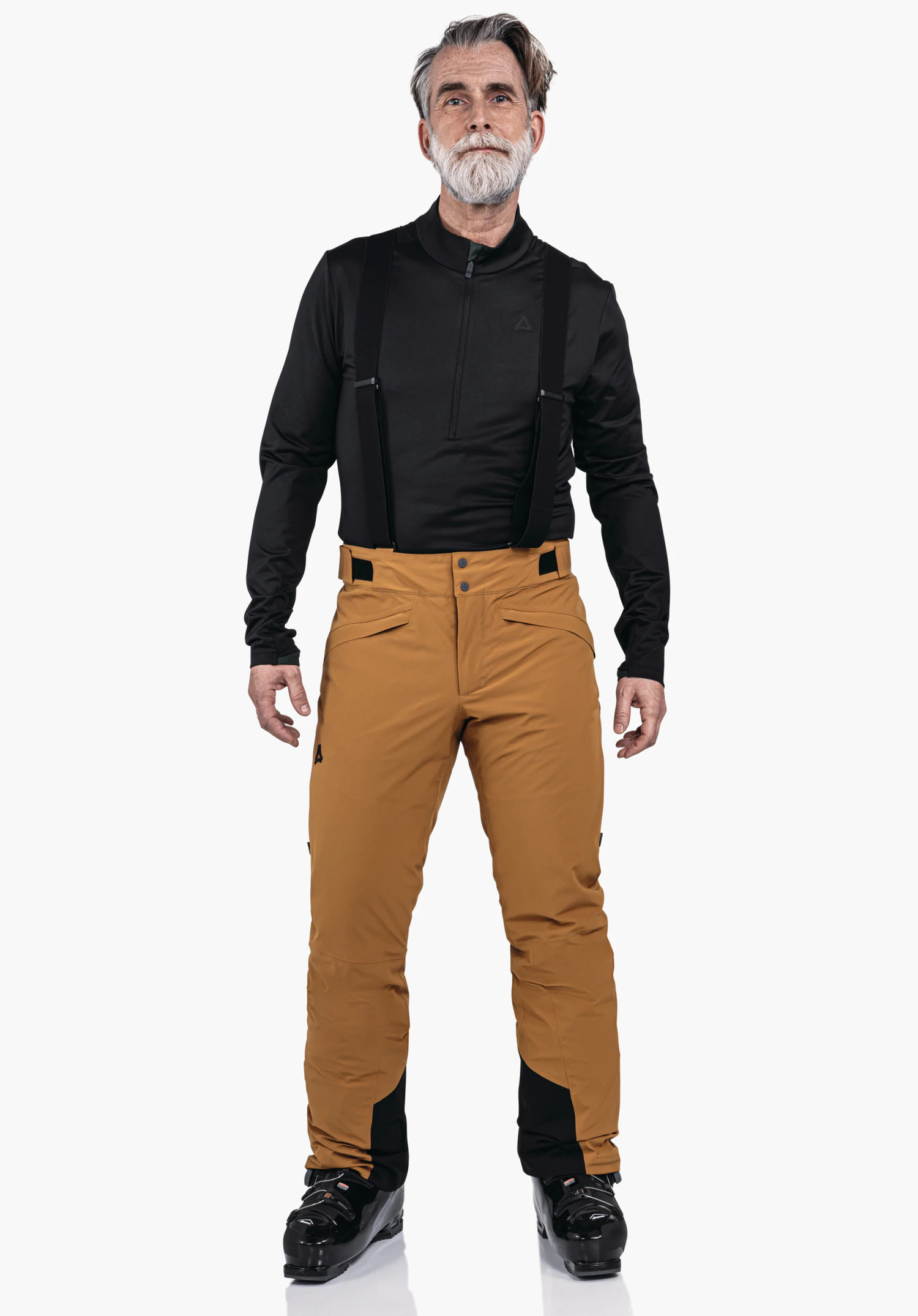 Pants Style Mountet MNS homme debout de face, portant un haut manches longues noir avec bretelles, un pantalon de ski orange foncé et des chaussures de ski noires; logo Schöffel sur la poitrine et la cuisse gauche; fond blanc.