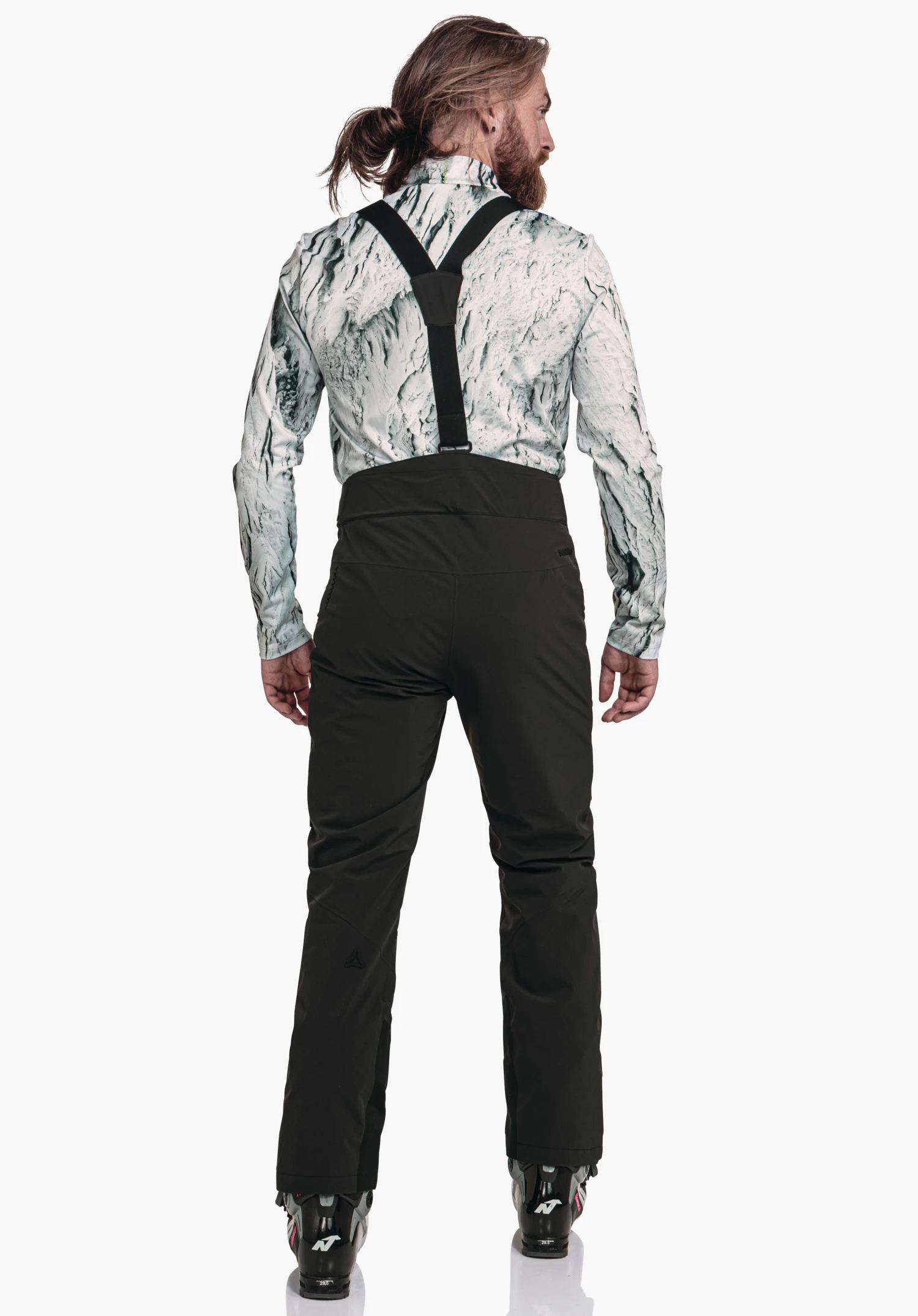 Pants Style Mountet MNS black ski trousers with black braces worn by a person from the back; white top with dark green pattern; ski boots visible; Schöffel logo visible.