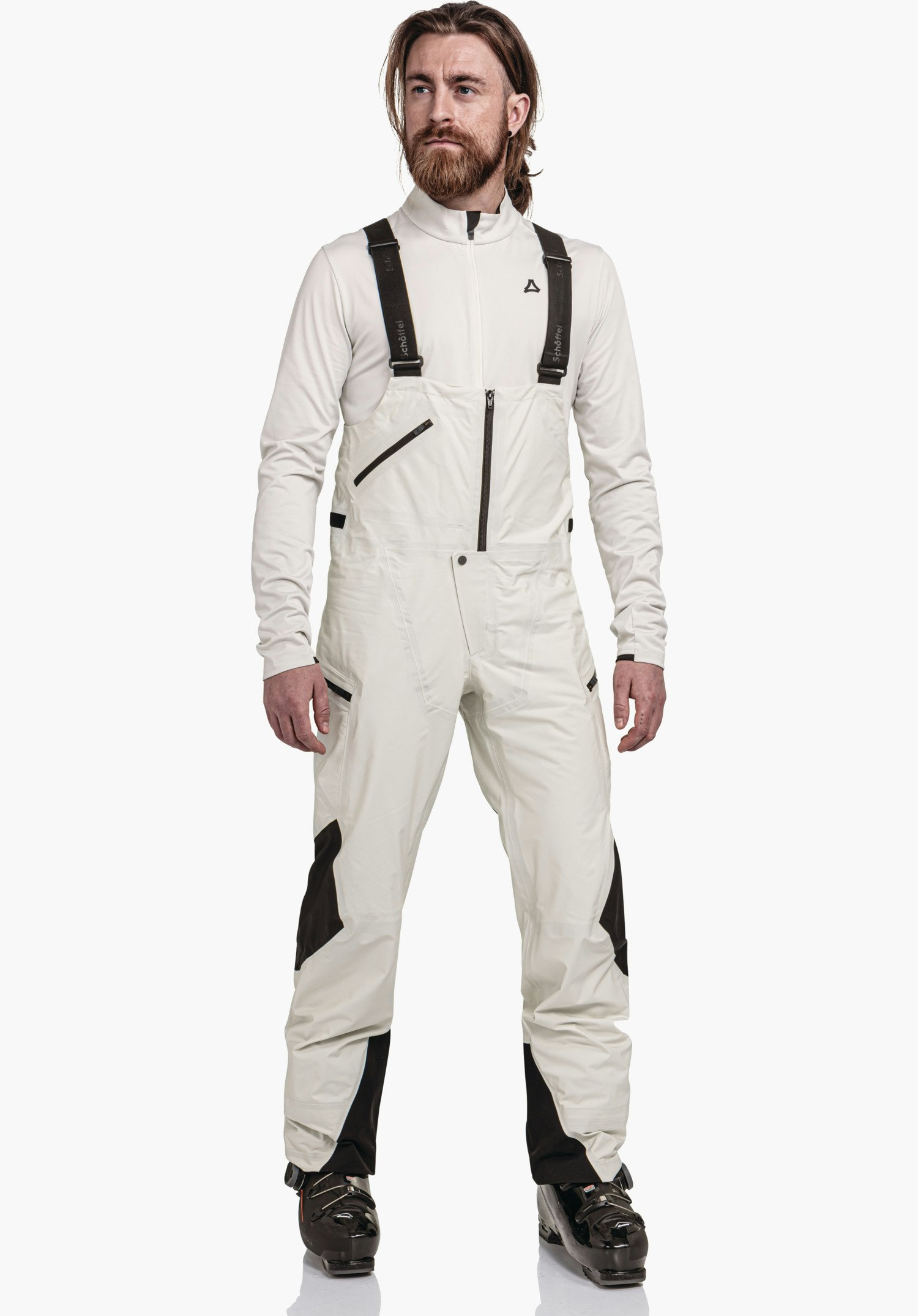 Pants Style Lufeld MNS salopette: man staat en draagt een lichtwitte salopette met zwarte applicaties en zwarte bretels; neutrale witte achtergrond. Schöffel-logo zichtbaar. Tekst op de bretels: "Schöffel".