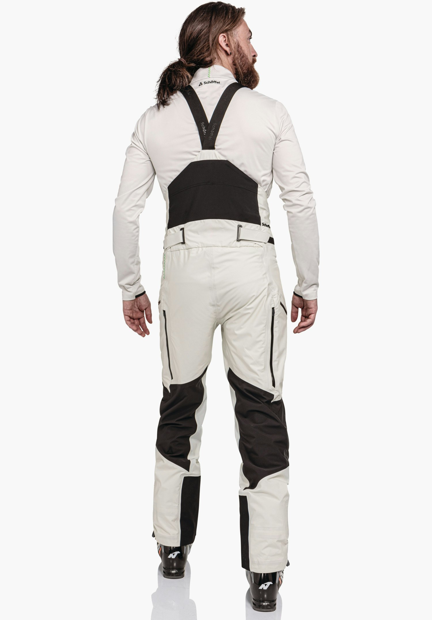 Pants Style Lufeld MNS man wearing off-white ski trousers with black bib; stands with his back to the camera against a light background. Text: “Schöffel” (on collar, braces and hip area); Schöffel logo on the collar.