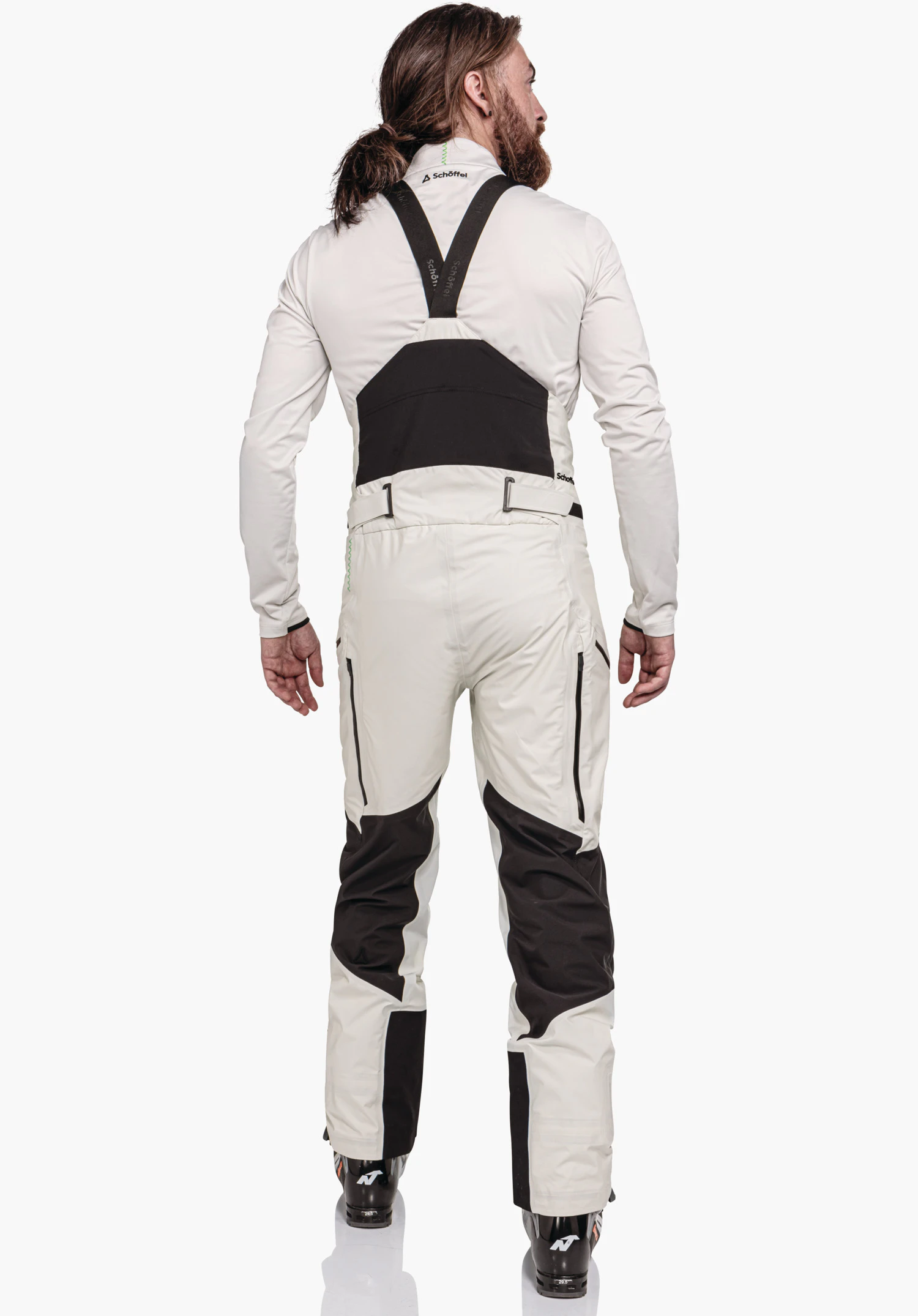 Pants Style Lufeld MNS man wearing off-white ski trousers with black bib; stands with his back to the camera against a light background. Text: “Schöffel” (on collar, braces and hip area); Schöffel logo on the collar.