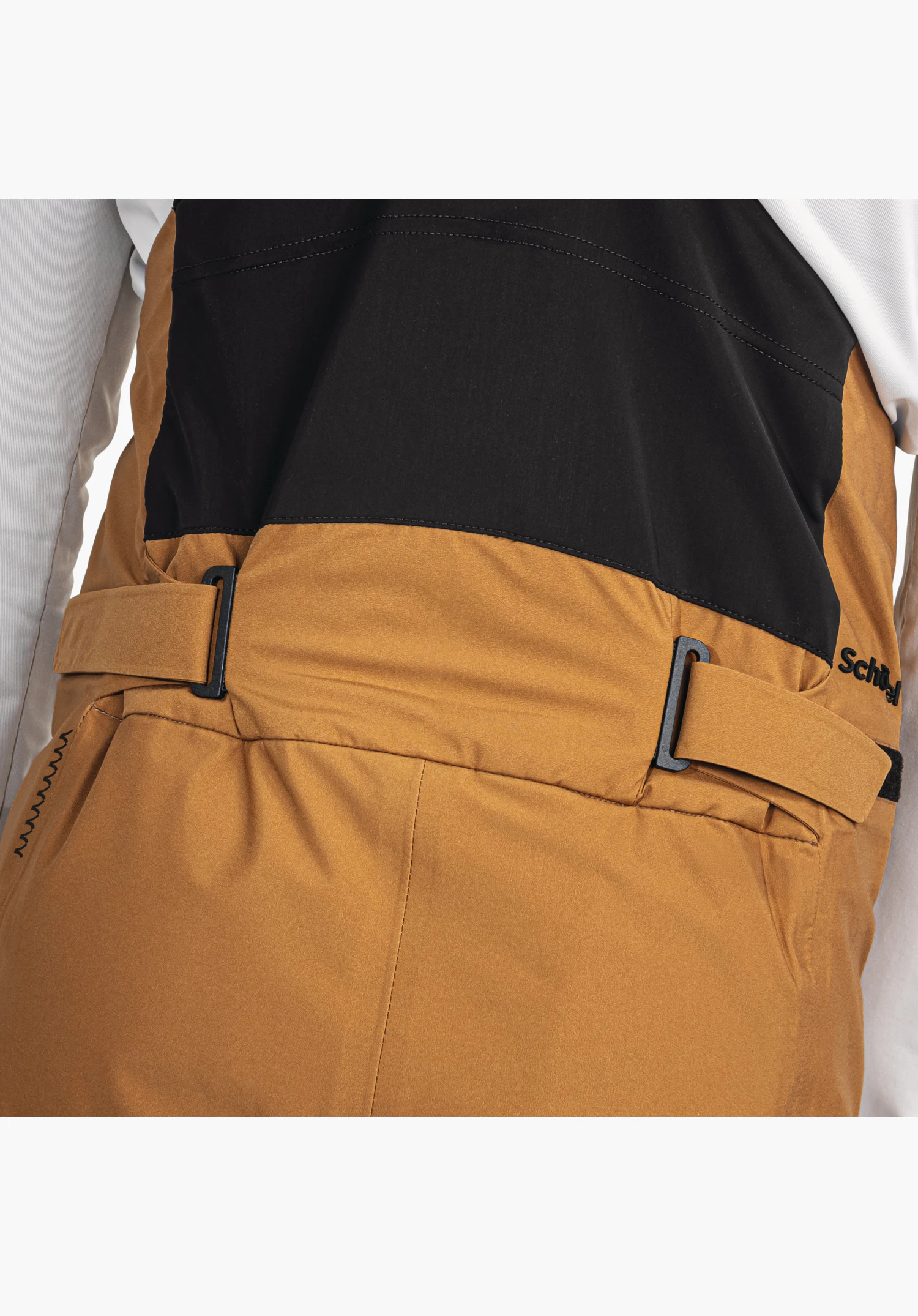 Pants Style Lufeld MNS zeigt den verstellbaren Taillenbund in Braun mit schwarzen Riegeln und dem Übergang zum schwarzen Rückeneinsatz sowie dem partiellen Schöffel-Logo. Nahaufnahme vor weißem/neutralem Hintergrund.