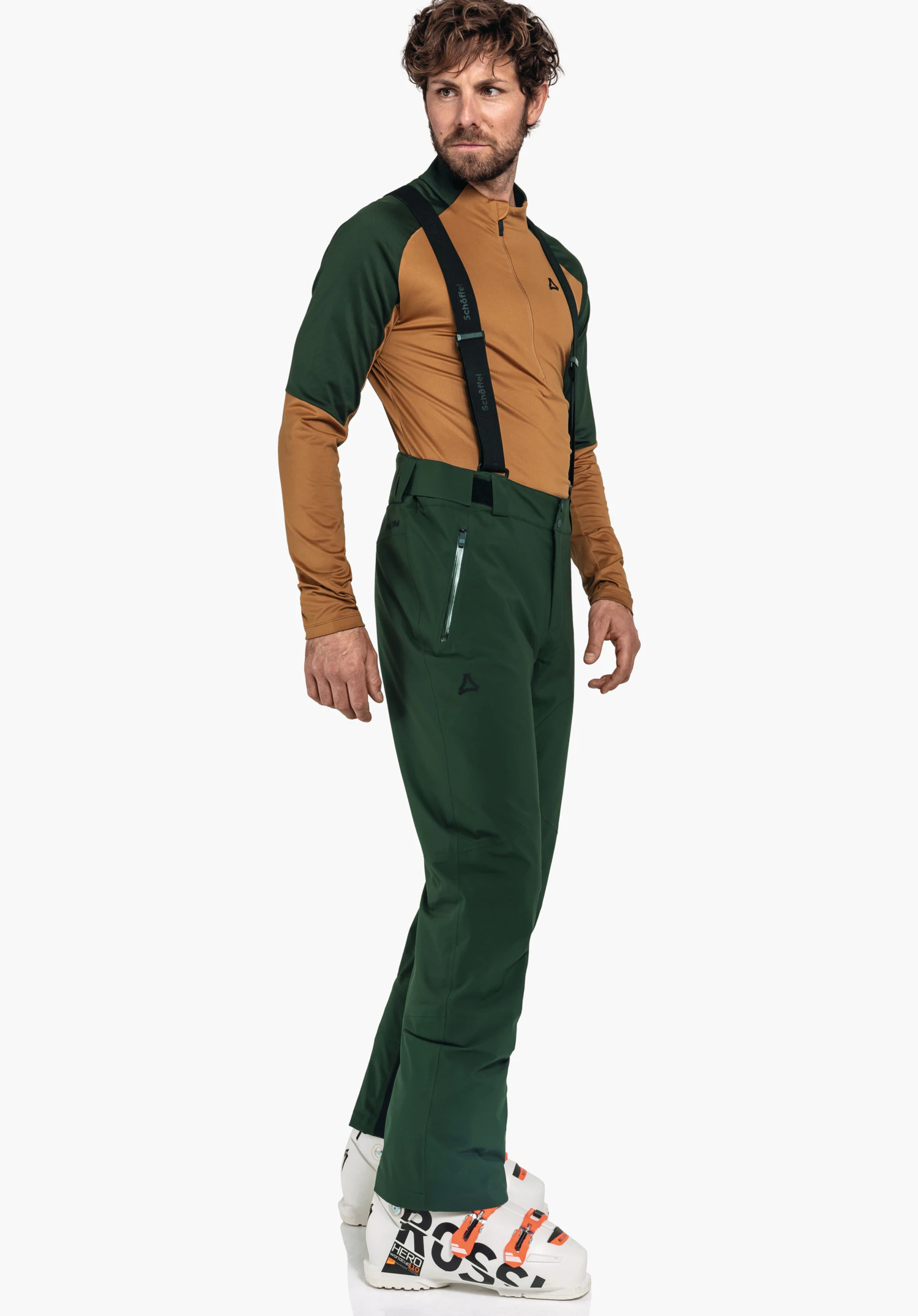 Pants Style Pine MNS homme portant un pantalon de ski vert foncé avec bretelles et un haut de sport brun clair, debout de profil; logo Schöffel sur la poitrine et le pantalon. Texte: "Schöffel" (bretelles); "HERO" (chaussures).