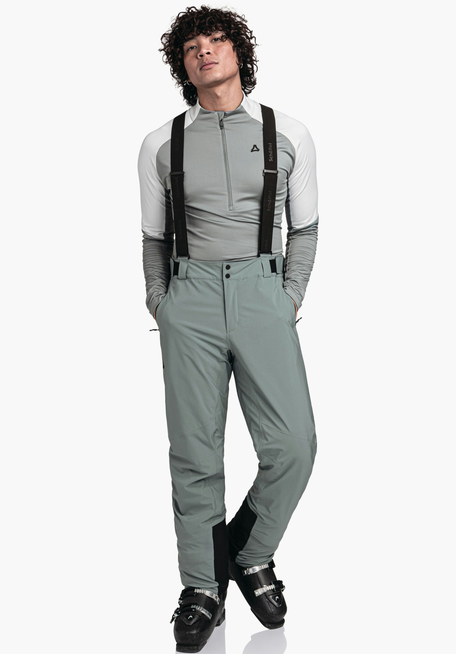 Pants Style Pine MNS Mann trägt hellgrünes Funktionsshirt mit weißen Ärmeln und hellgrüne Skihose, trägt schwarze Hosenträger; Schöffel-Logo auf Brust; Schrift auf Trägern: "Schöffel". Auf weißem Hintergrund.