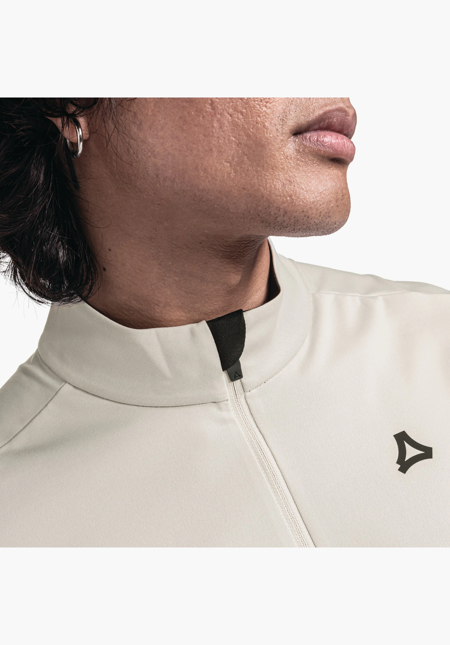 Longsleeve Style Pine MNS présente le col avec demi-zip, le protège-menton foncé et le logo Schöffel sur le tissu nature ; gros plan sur fond blanc.