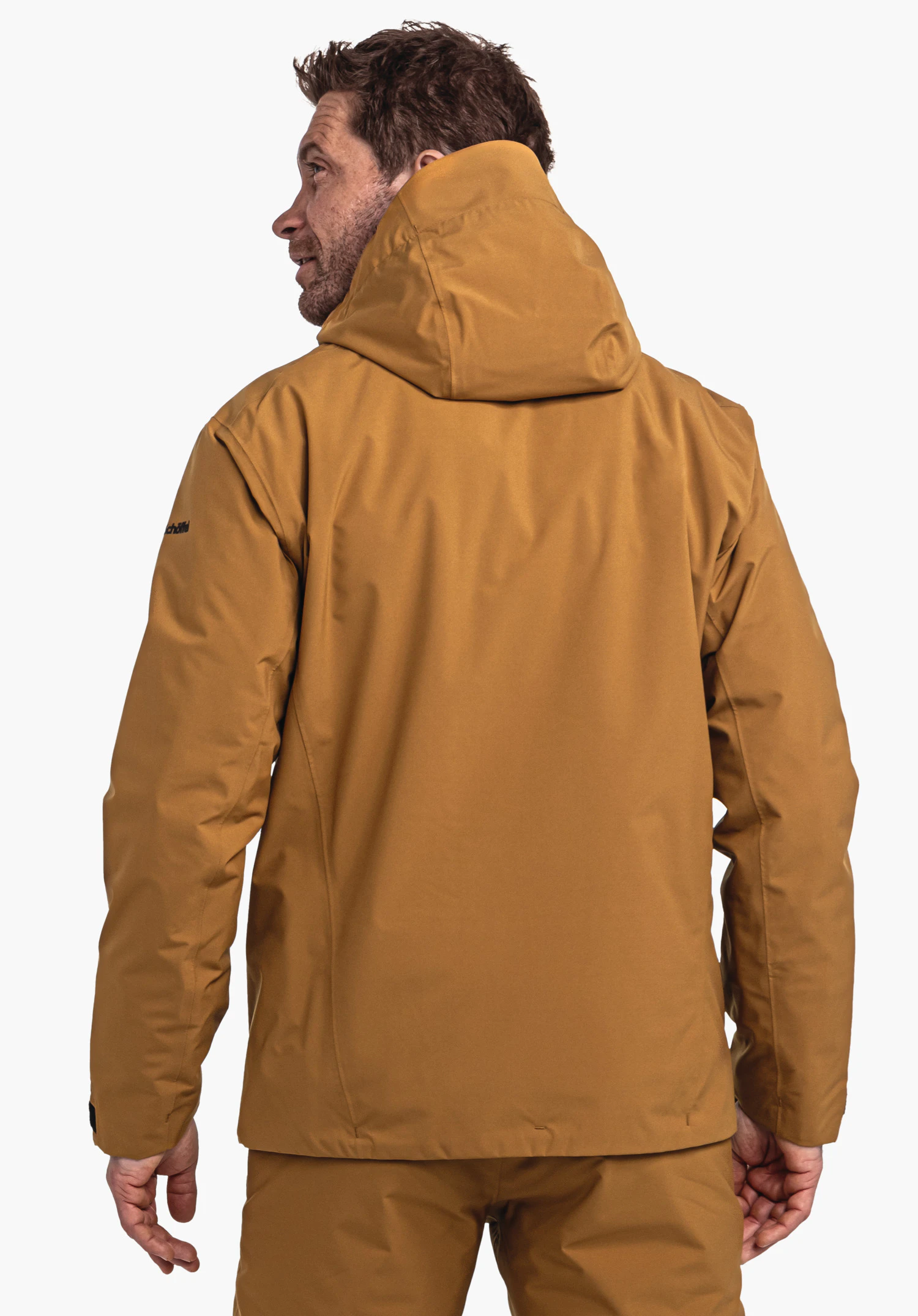 Jacket Style Nollen MNS donkergele jas, gedragen door een persoon; staat met de rug naar de camera voor een witte achtergrond. Tekst op de linkermouw: "Schöffel".