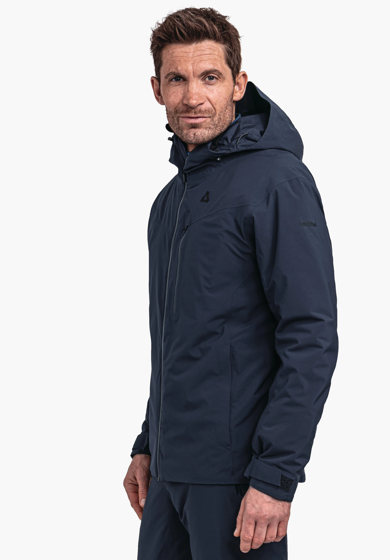 Jacket Style Nollen MNS veste bleu foncé à capuche, portée par un homme debout légèrement tourné de côté; logo Schöffel sur la poitrine; fond blanc. Texte: "Schöffel".