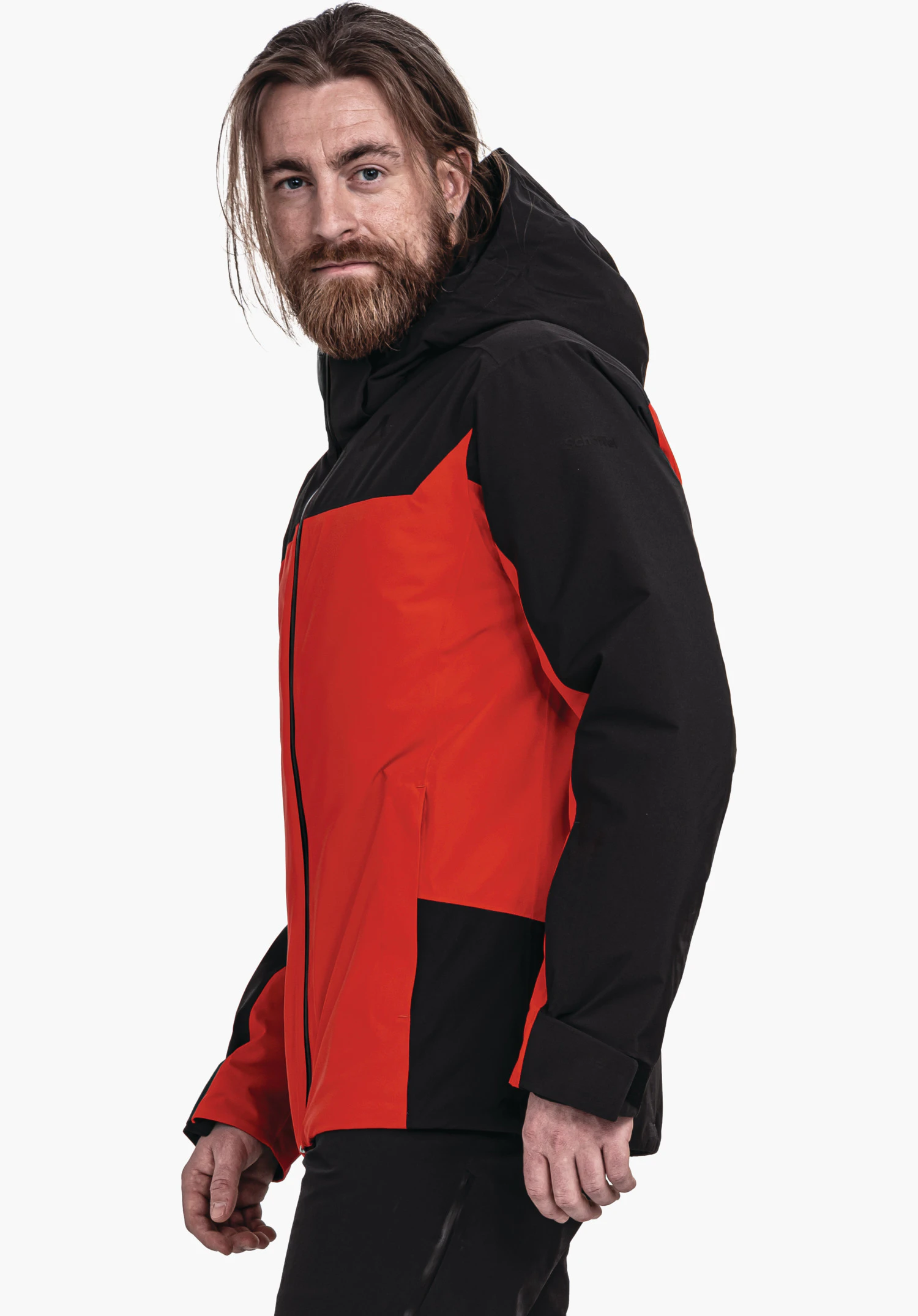 Jacket Style Zandwel MNS veste rouge avec capuche noire et manches noires; un homme barbu la porte debout en demi-profil devant fond clair neutre.