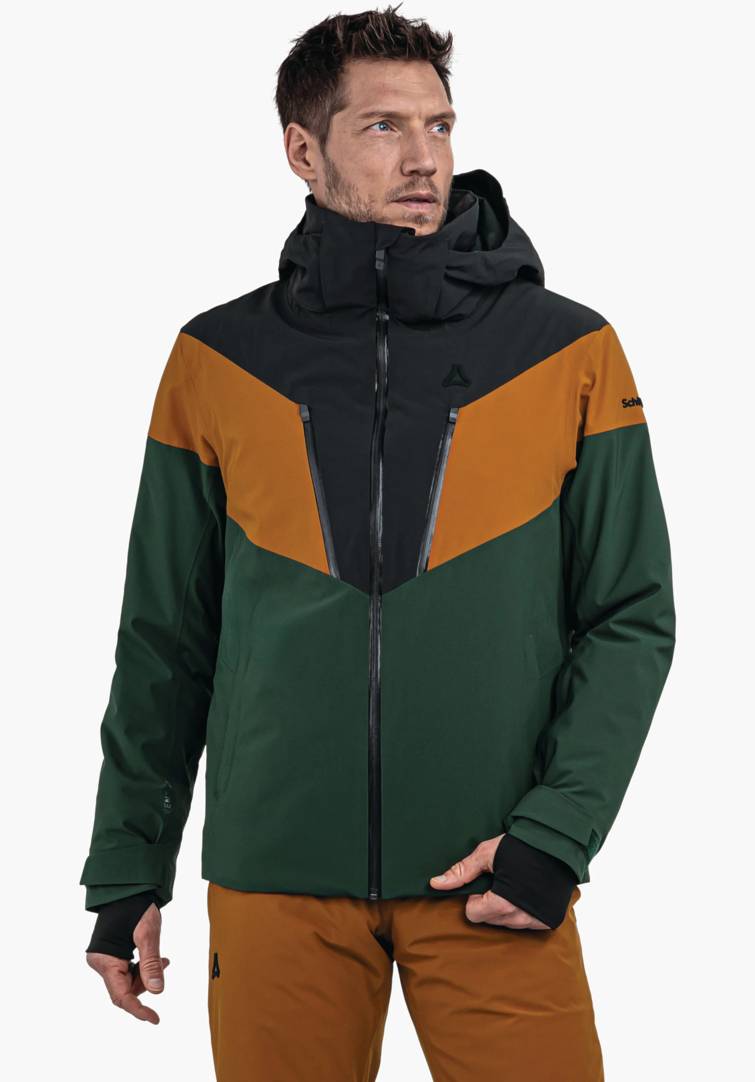 Jacket Style Safuna MNS veste vert foncé, orange et noire portée par un homme debout regardant de côté devant un fond clair; logo Schöffel sur la poitrine; inscription sur la manche:Schöffel.