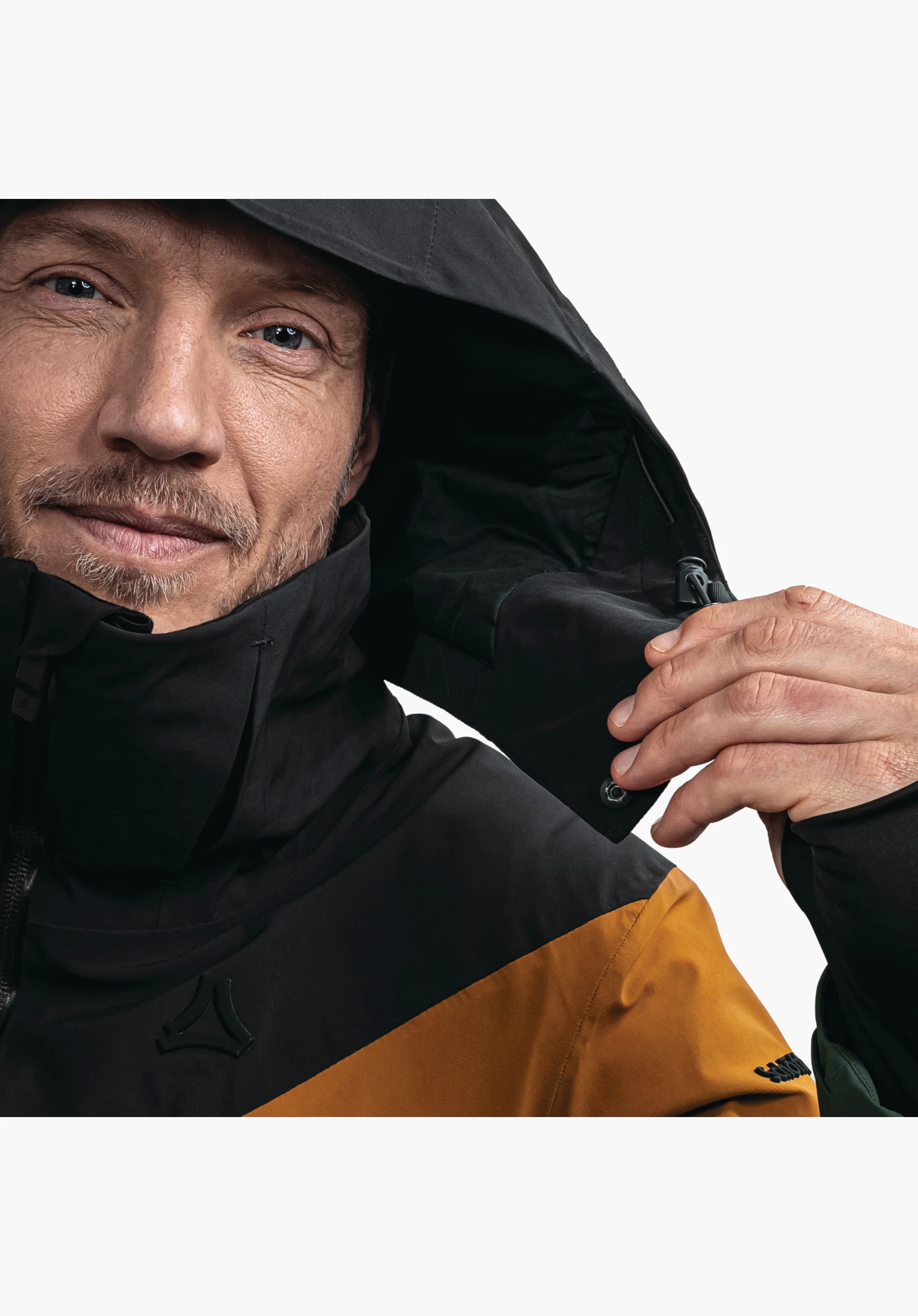 Jacket Style Safuna MNS, vue détaillée du col haut et de la capuche avec bouton-pression ainsi que du logo Schöffel sur la poitrine noire avec empiècement jaune de ce modèle vert, gros plan sur fond blanc/neutre.