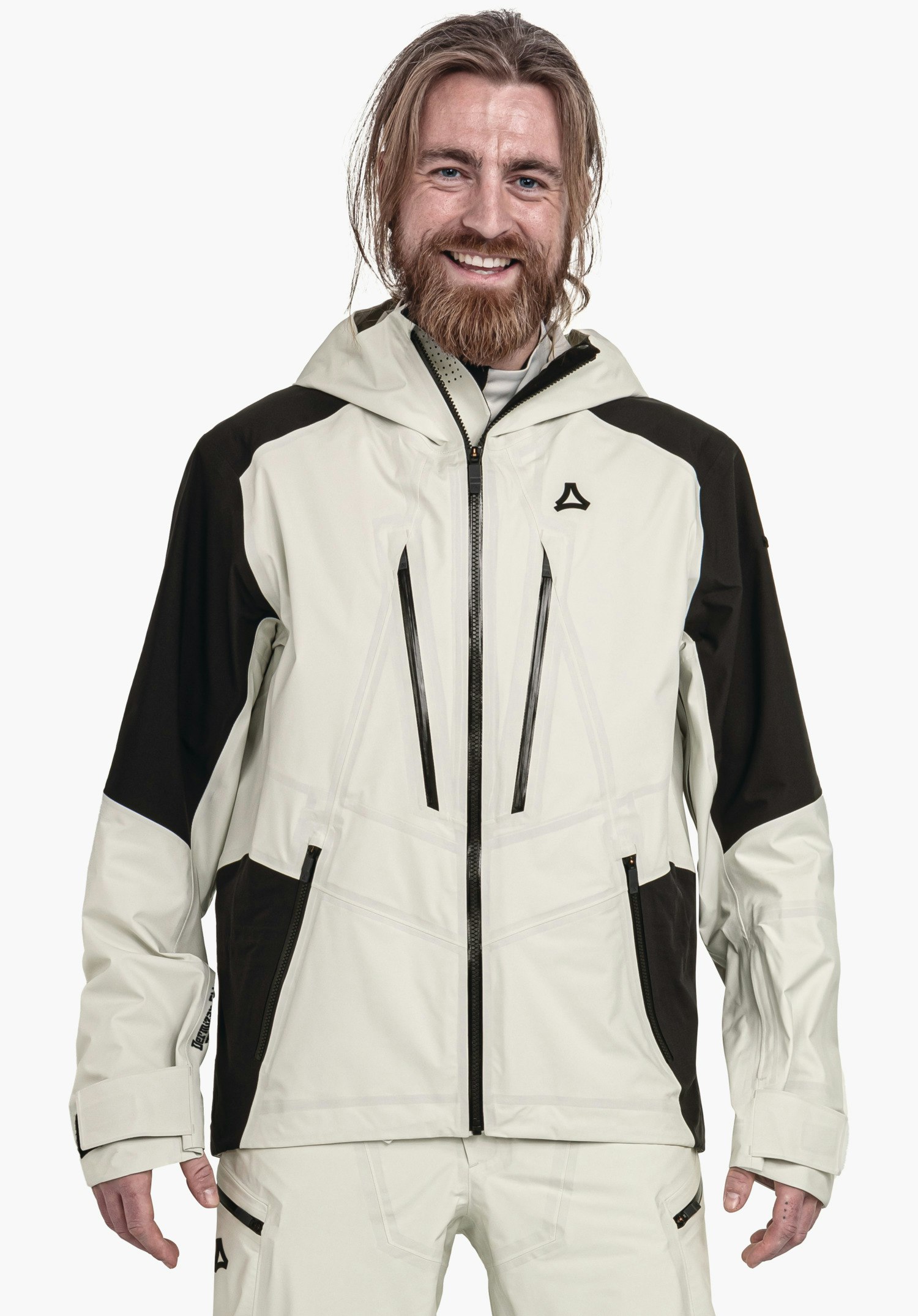 Shell Jk Style Lufeld MNS hellgraue Outdoorjacke mit schwarzen Einsätzen, Schöffel-Logo auf der Brust; Person trägt sie lächelnd, steht frontal vor neutralem weißem Hintergrund.