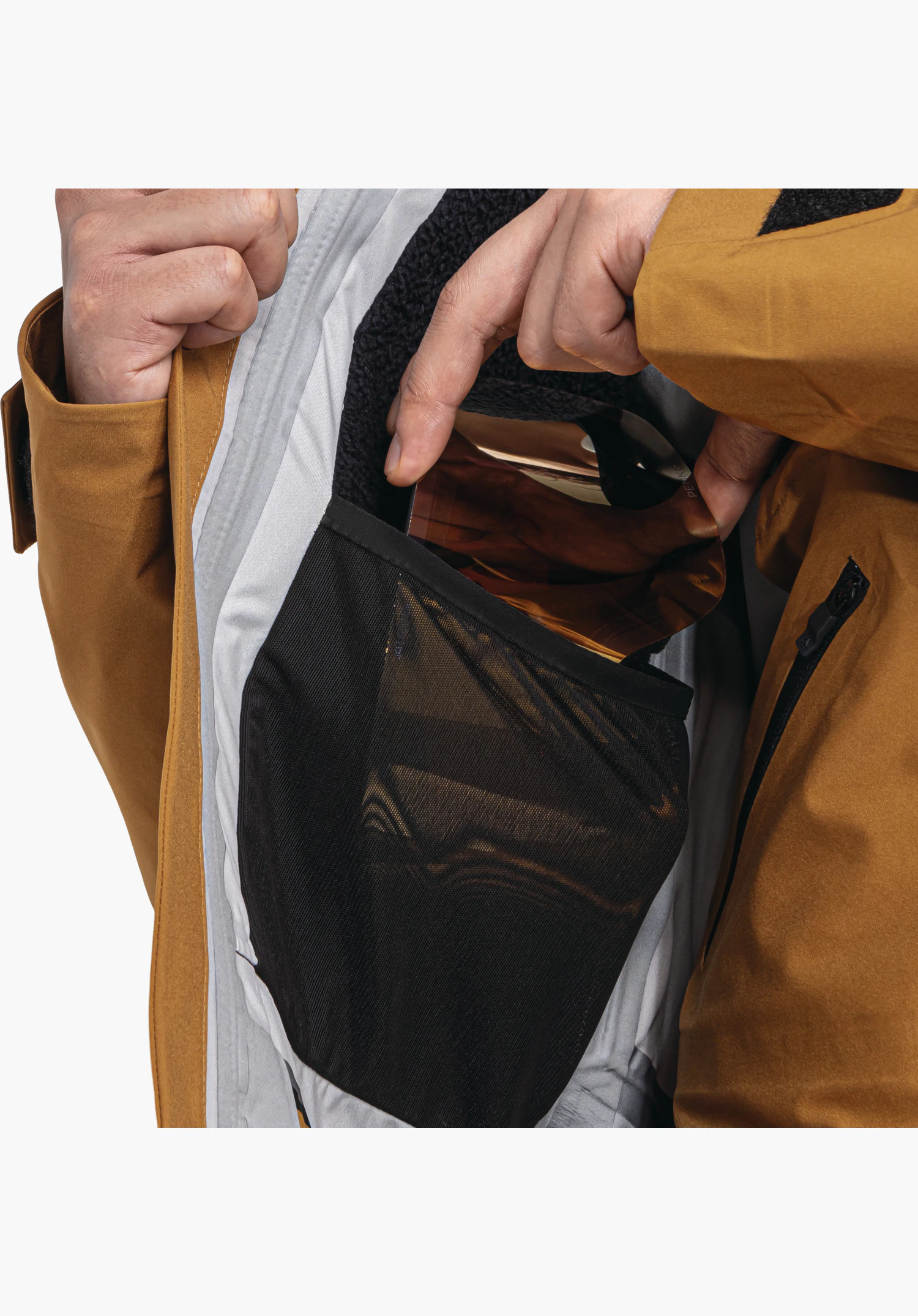 Shell Jk Style Lufeld MNS Innenseite mit einer geräumigen Mesh-Tasche für die Skibrille bei geöffneter brauner Jacke, Nahaufnahme vor weißem Hintergrund.
