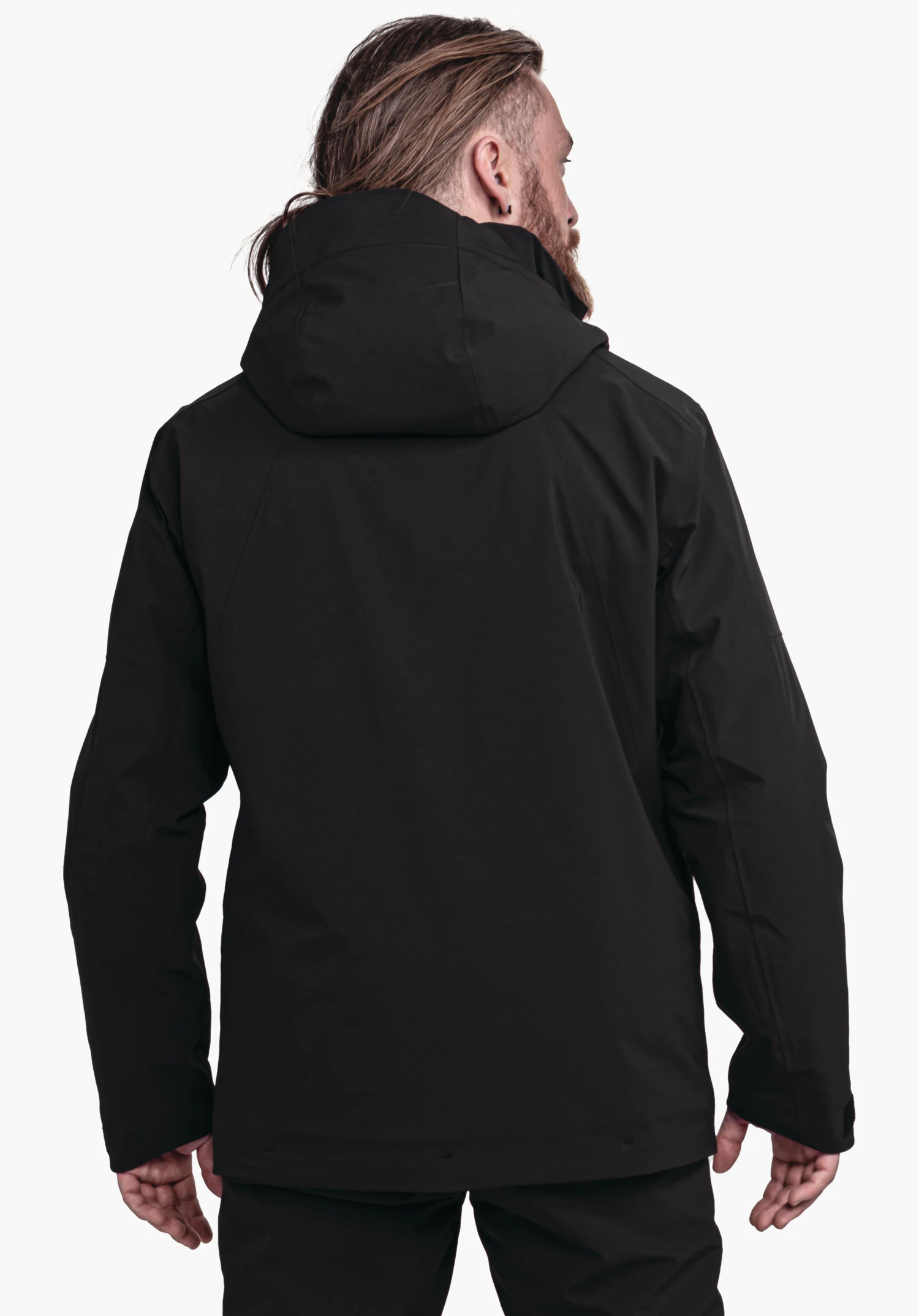 Jacket Style Skuta MNS Schwarze Jacke mit Kapuze, getragen von einer stehenden Person von hinten; Person steht vor weißem hellem Hintergrund, Hände seitlich, Kopf nach rechts gedreht.