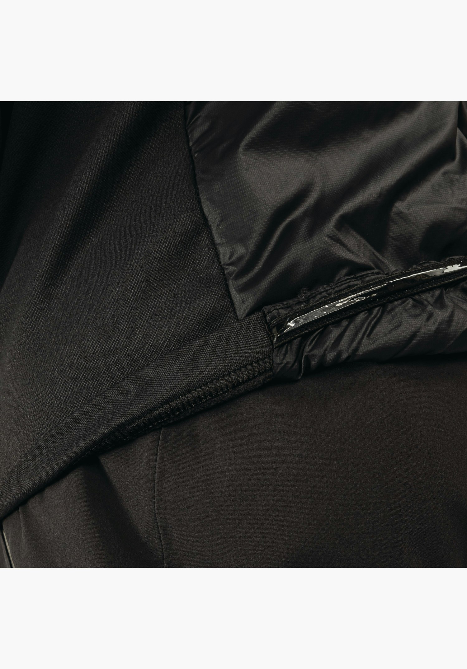 Ins Jacket Style Pontre MNS shows the elasticated hem with silicone anti-slip tape and the mix of matte and shiny black fabric as a close-up against a white/neutral background.