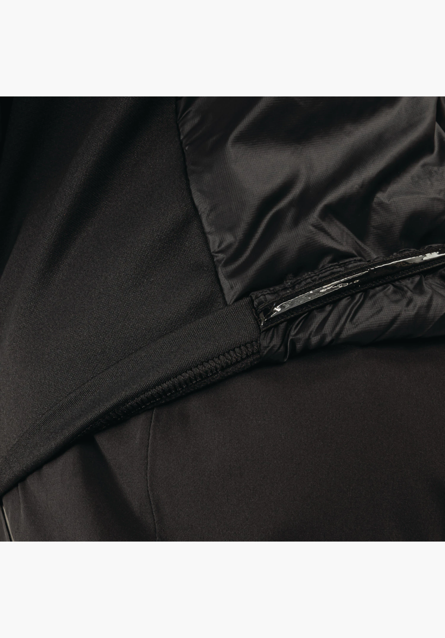Ins Jacket Style Pontre MNS shows the elasticated hem with silicone anti-slip tape and the mix of matte and shiny black fabric as a close-up against a white/neutral background.