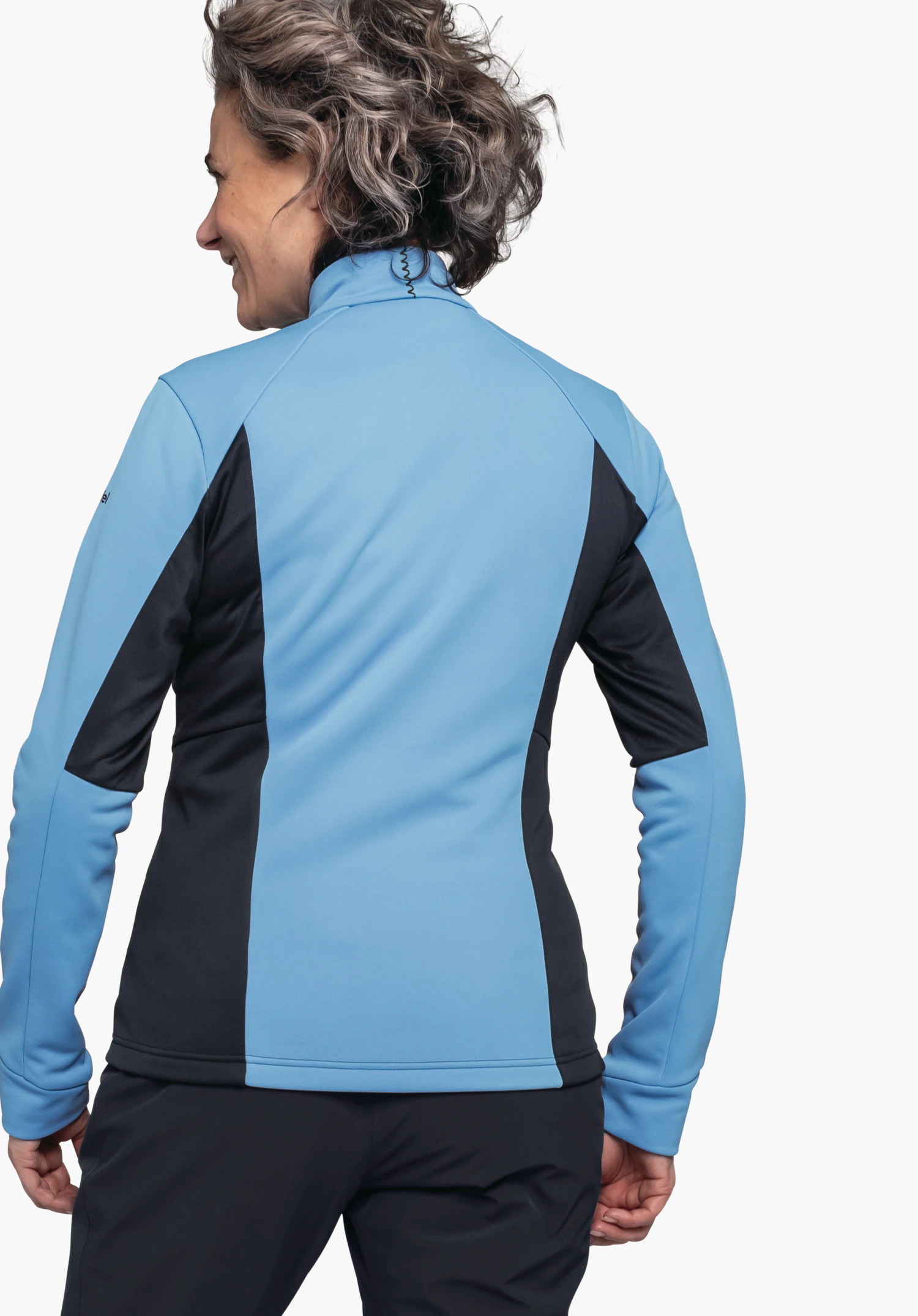 Fleece Jk Style Pontre WMS Frau trägt hellblau-dunkelblau Softshelljacke, steht mit Rücken zur Kamera und leicht nach links gewandt, Arme entspannt an den Seiten; neutraler weißer Studiohintergrund.