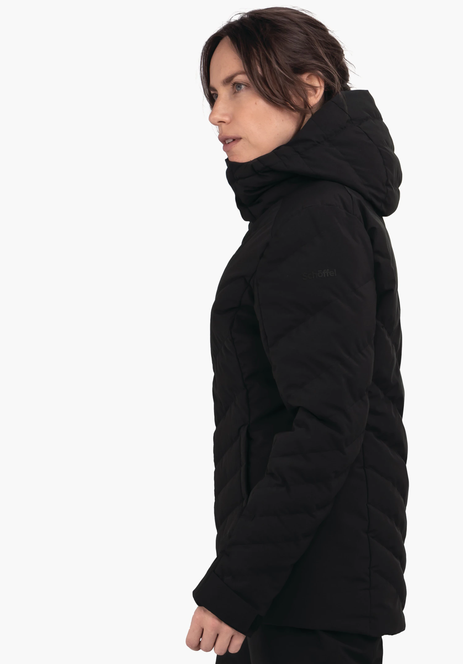 Jacket Style Alerce WMS zwarte doorgestikte jas met capuchon, zijwaarts gedragen door een vrouw die naar links kijkt voor een witte achtergrond. Tekst op de jas: "schöffel".