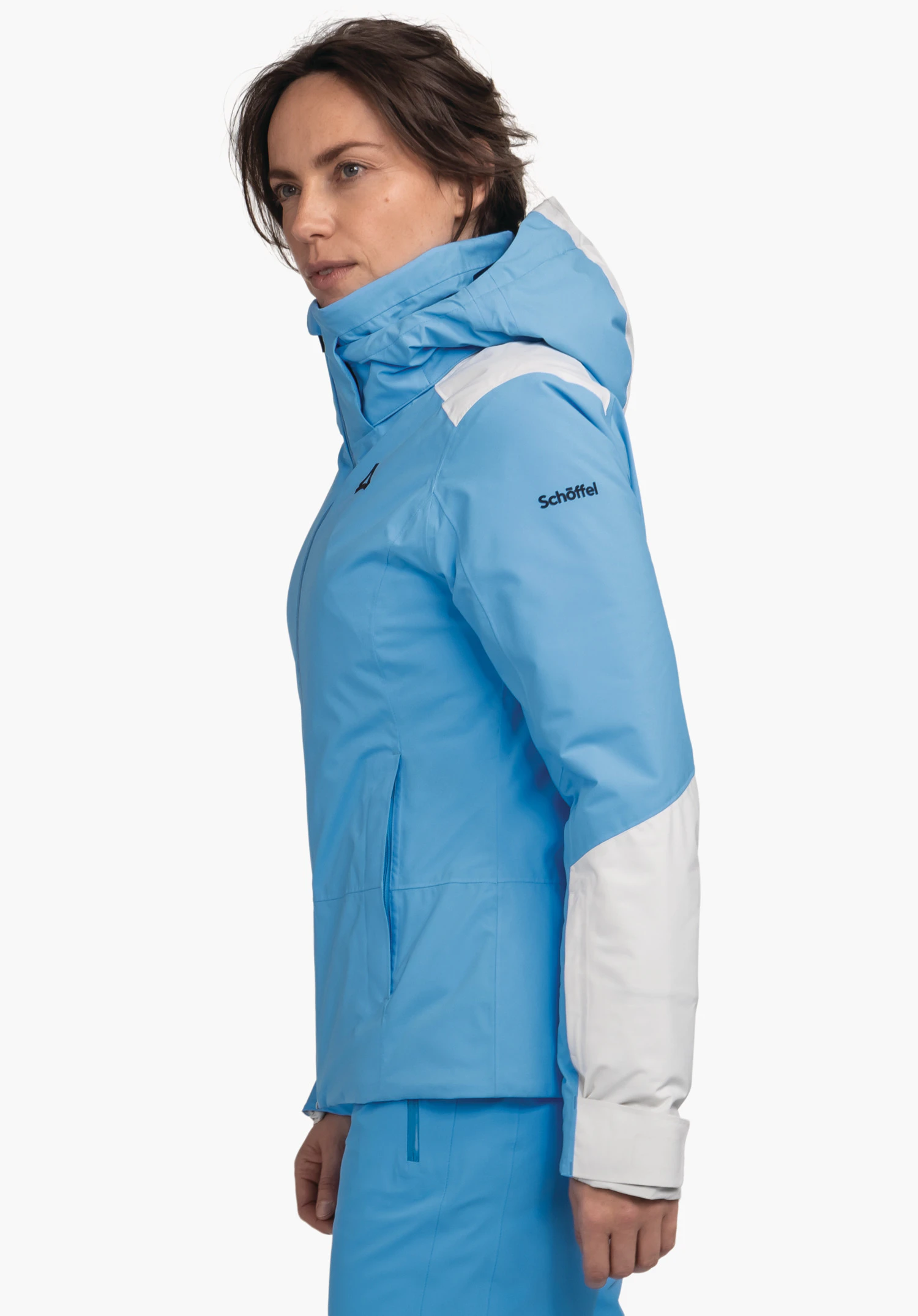 Jacket Style Zandwel WMS veste blanc clair avec finitions noires; femme la porte fermée, debout en vue de profil devant fond clair. Logo Schöffel sur la poitrine et le bonnet; inscription "Schöffel" sur la manche.