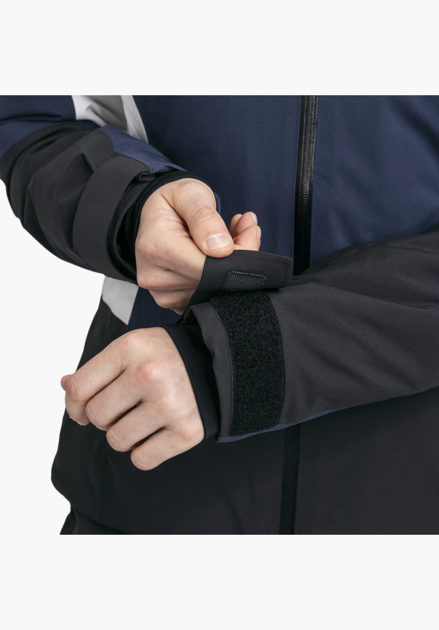 Jacket Style Zandwel WMS en bleu montre le poignet réglable avec fermeture auto-agrippante et poignet intérieur élastique en gros plan sur fond blanc.