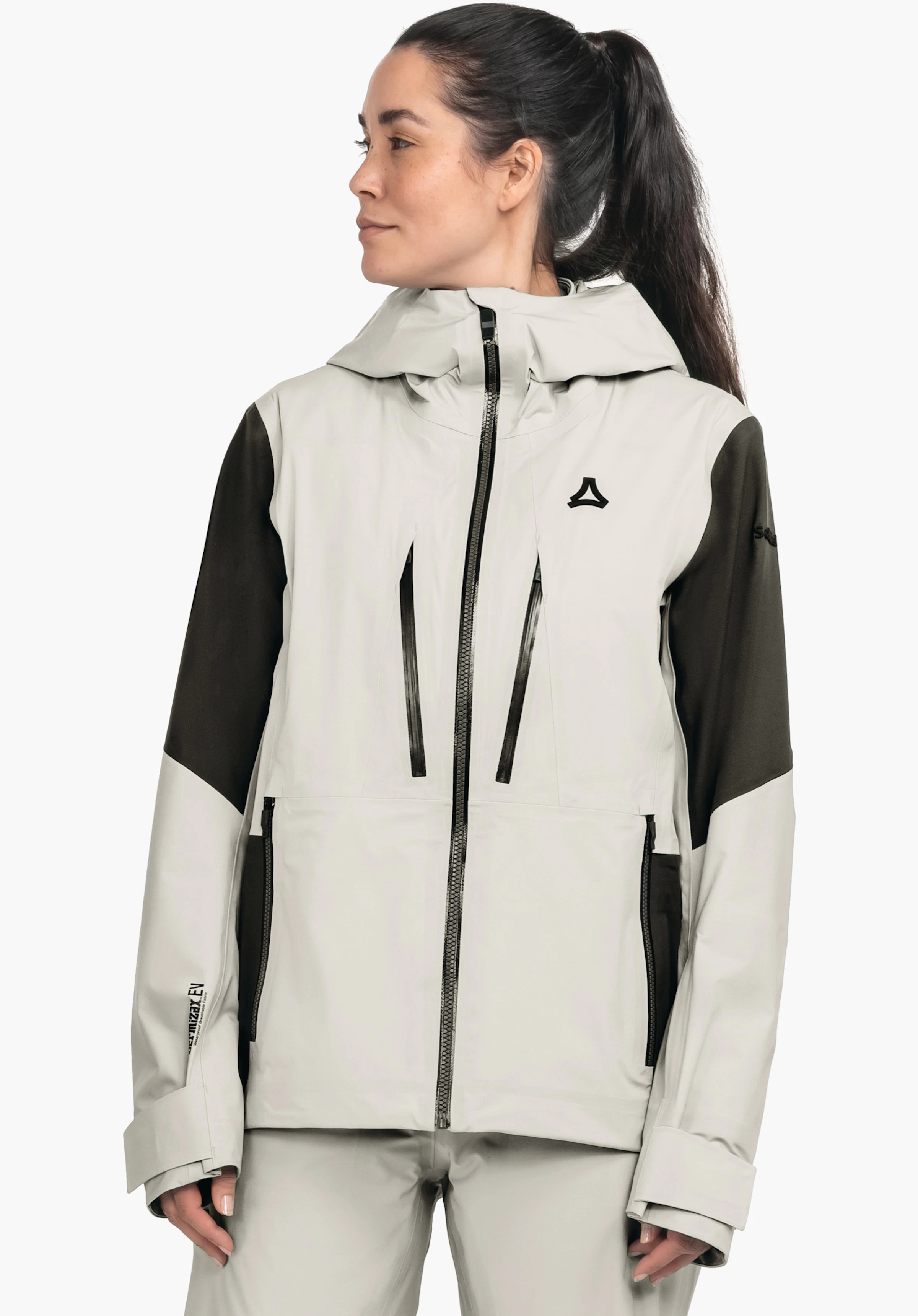 Shell Jk Style Lufeld WMS witte jas met donkergroene mouwen, Schöffel-logo op de borst; gedragen door een vrouw met paardenstaart die zijwaarts kijkt, witte studioachtergrond. Geen leesbare tekst.