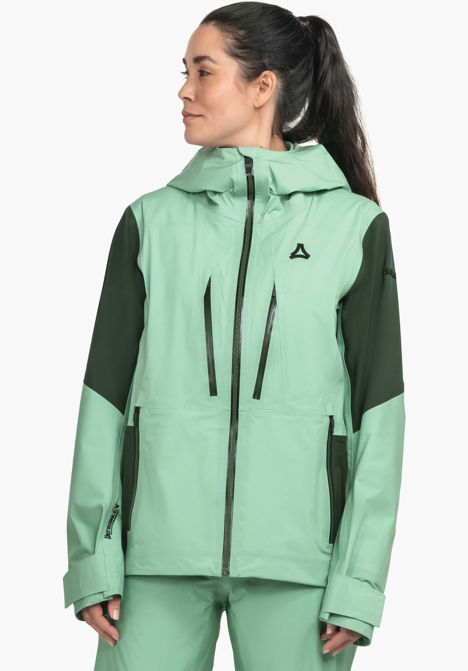 Shell Jk Style Lufeld WMS Jacke grün hell: Person trägt Jacke, steht und blickt nach links; Kapuze hoch, Reißverschlüsse vorne sichtbar; Ärmel grün dunkel; Hintergrund weiß. Schöffel-Logo; DERMIZAX EV