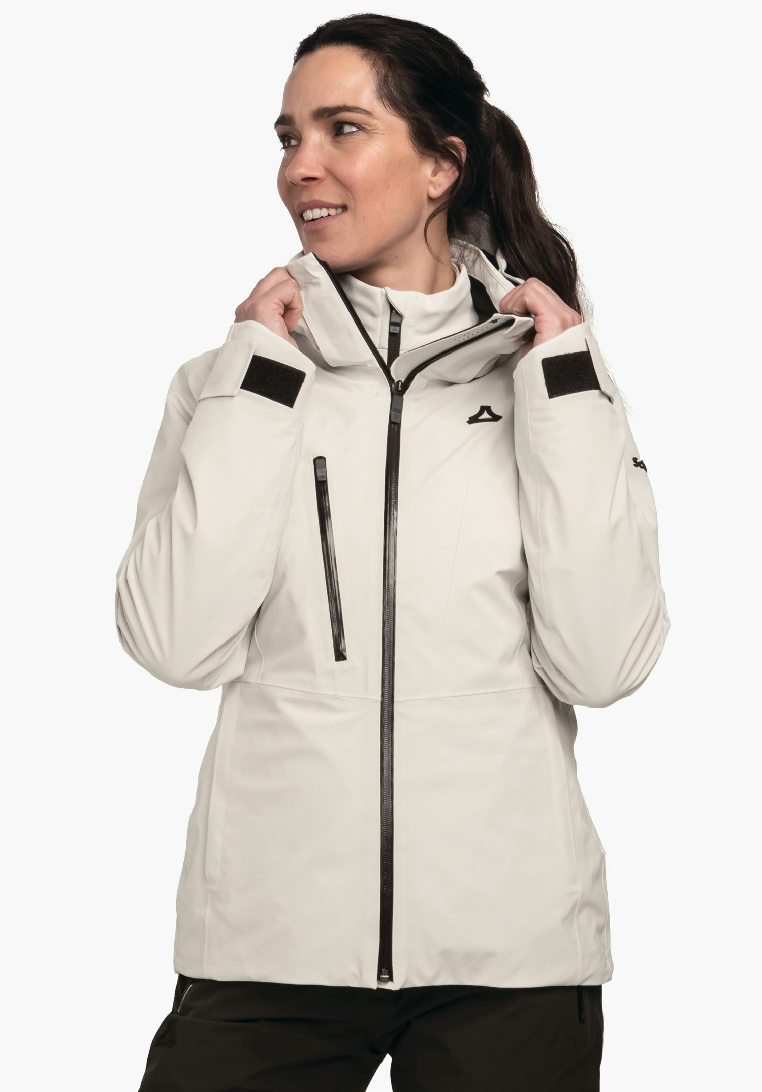 Jacket Style Pontre WMS jacket worn by a person pulling the collar up; off-white longer outdoor jacket with black zip, black chest zip and Schöffel logo; standing against a white background.