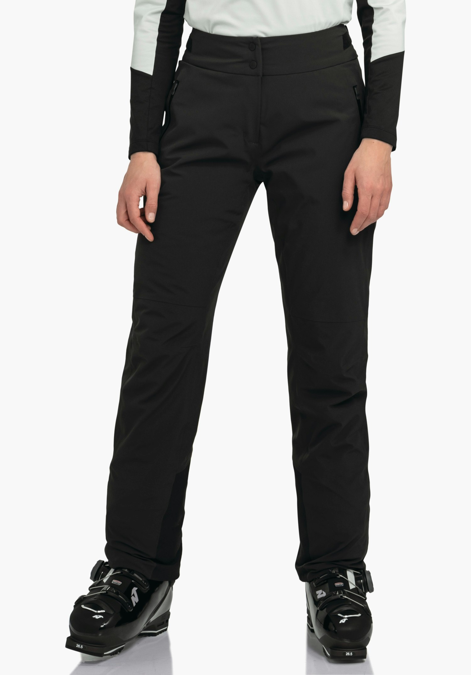 Pants Style Skayra WMS zwarte skibroek; persoon staat rechtop met handen langs het lichaam, draagt witte mouwen en zwarte skischoenen. Studio-omgeving, witte achtergrond. Tekst op schoen: 26.5.