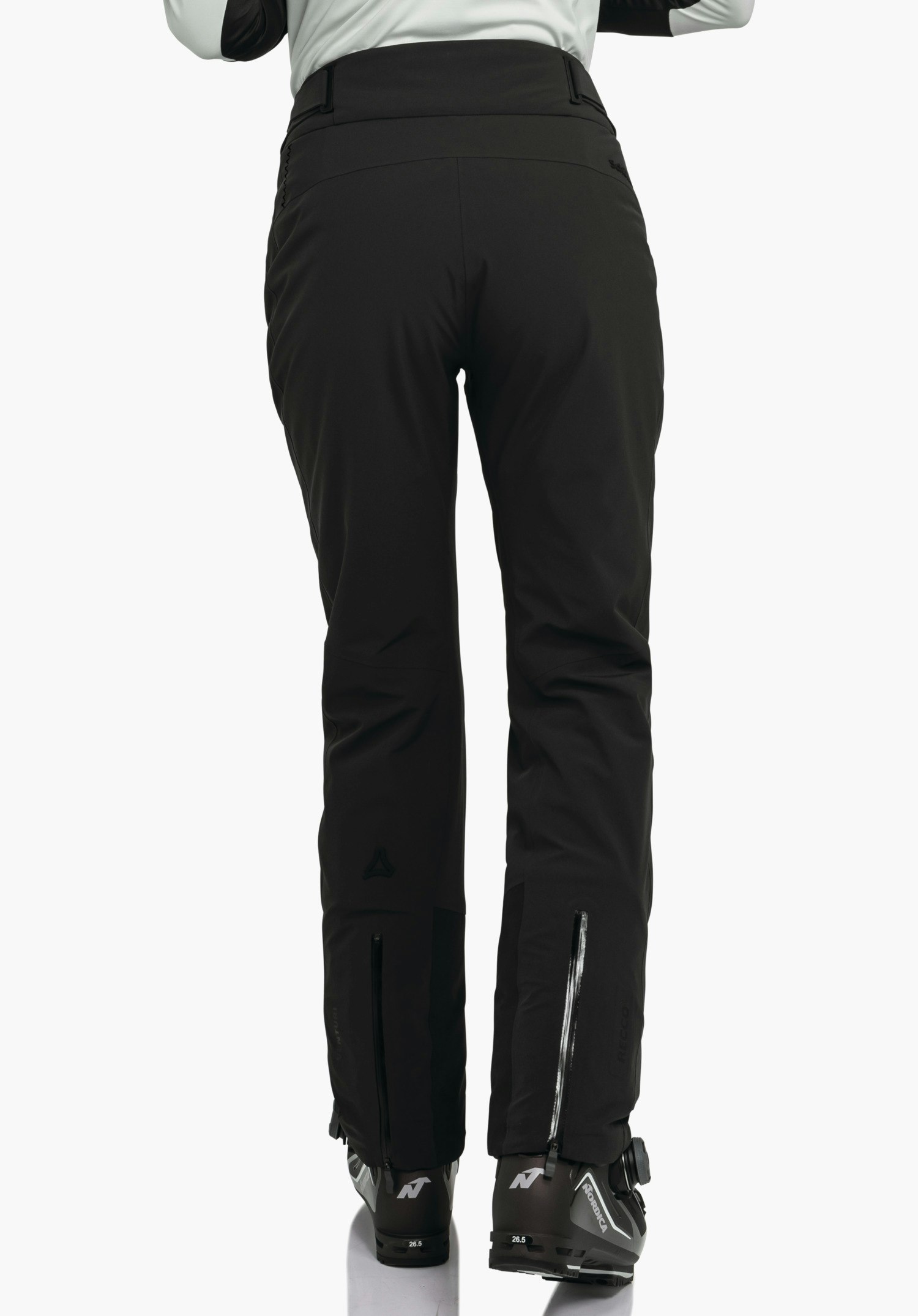 Pants Style Skayra WMS zwarte skihose, gedragen door een persoon in achteraanzicht voor een witte achtergrond; skischoenen met opschrift "N" en "26.5" zichtbaar, Schöffel-logo op het onderbeen.