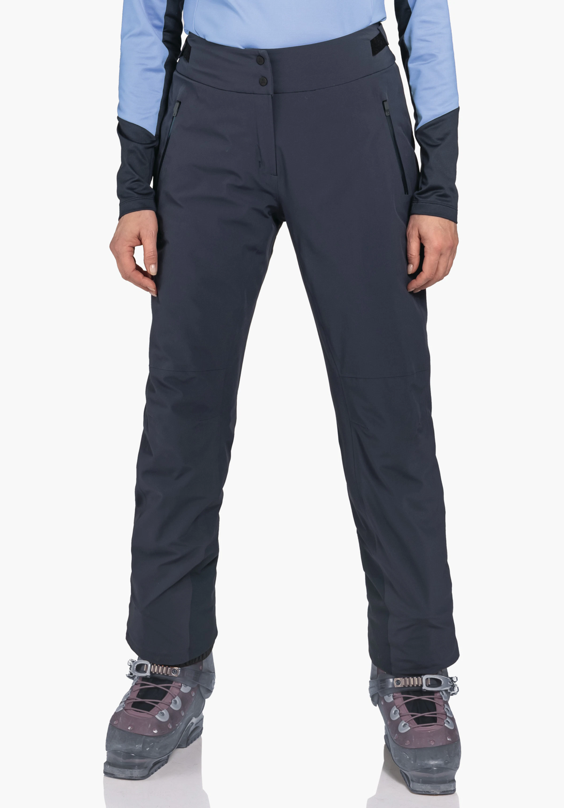 Pants Style Skayra WMS Dunkelblaue Outdoorhose; frontal abgebildet, trägt Person sie stehend mit leicht gespreizten Beinen; hellblaues Oberteil, dunkelrote Bergschuhe mit dunkelgrauen Details, weißer Hintergrund.