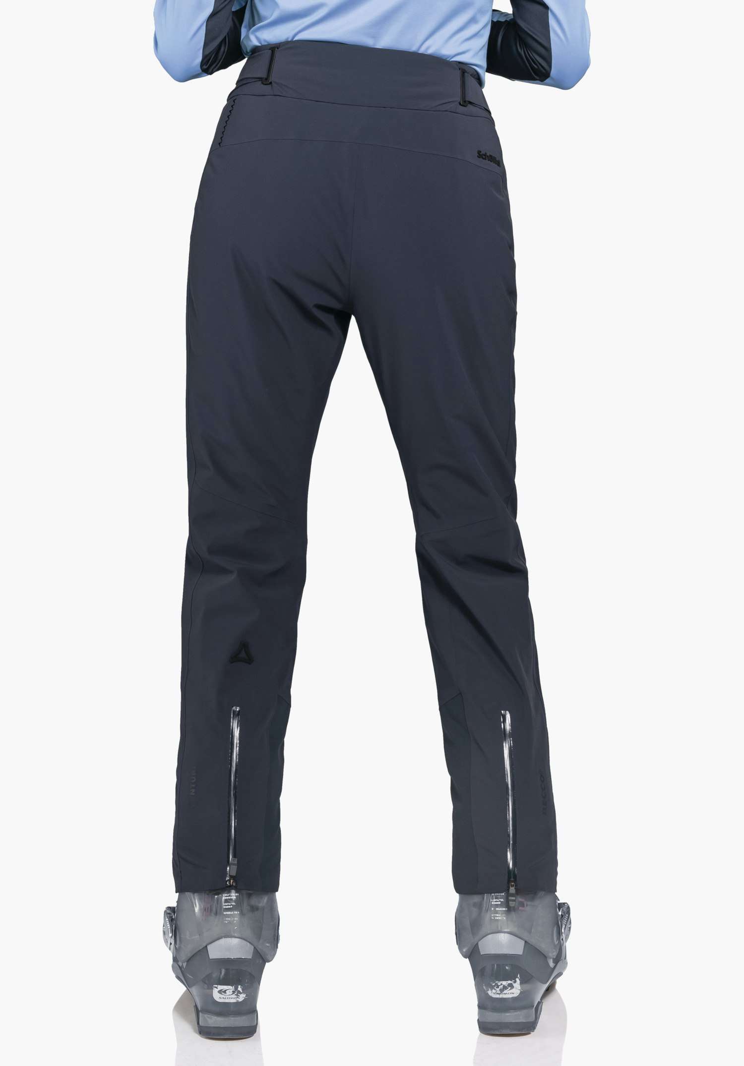 Pants Style Skayra WMS donkerblauwe skihose, gedragen door een staande persoon met licht gespreide benen in achteraanzicht; Schöffel-logo op de linker kuit, lichtblauw bovenstuk, grijze skischoenen, witte achtergrond. Tekst: "Schöffel".
