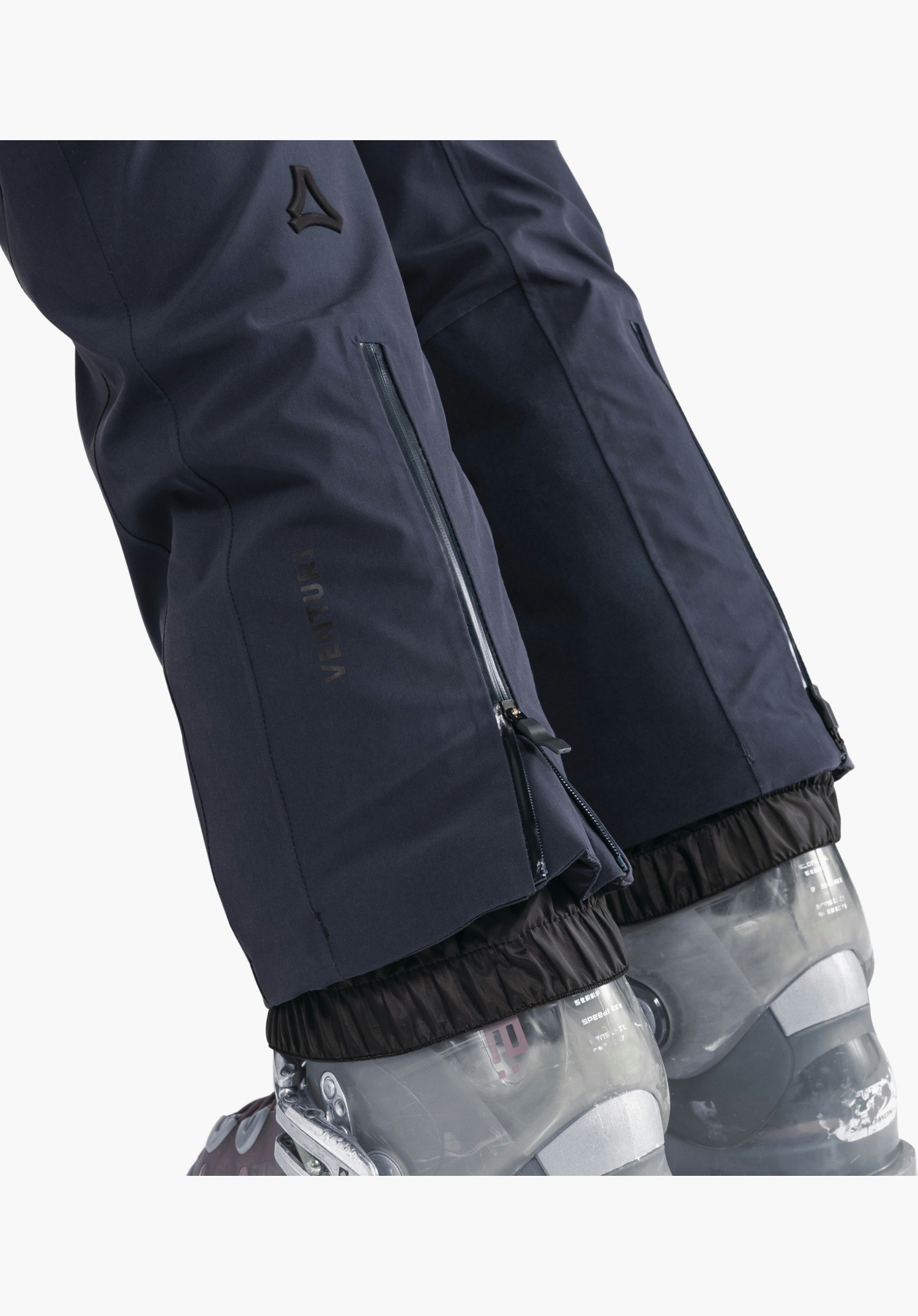 Pants Style Skayra WMS toont de blauwe broekspijpen met ritsen aan de zijkant, het Venturi-opschrift en het Schöffel-logo boven de sneeuwvanger als close-up voor een witte/neutrale achtergrond.