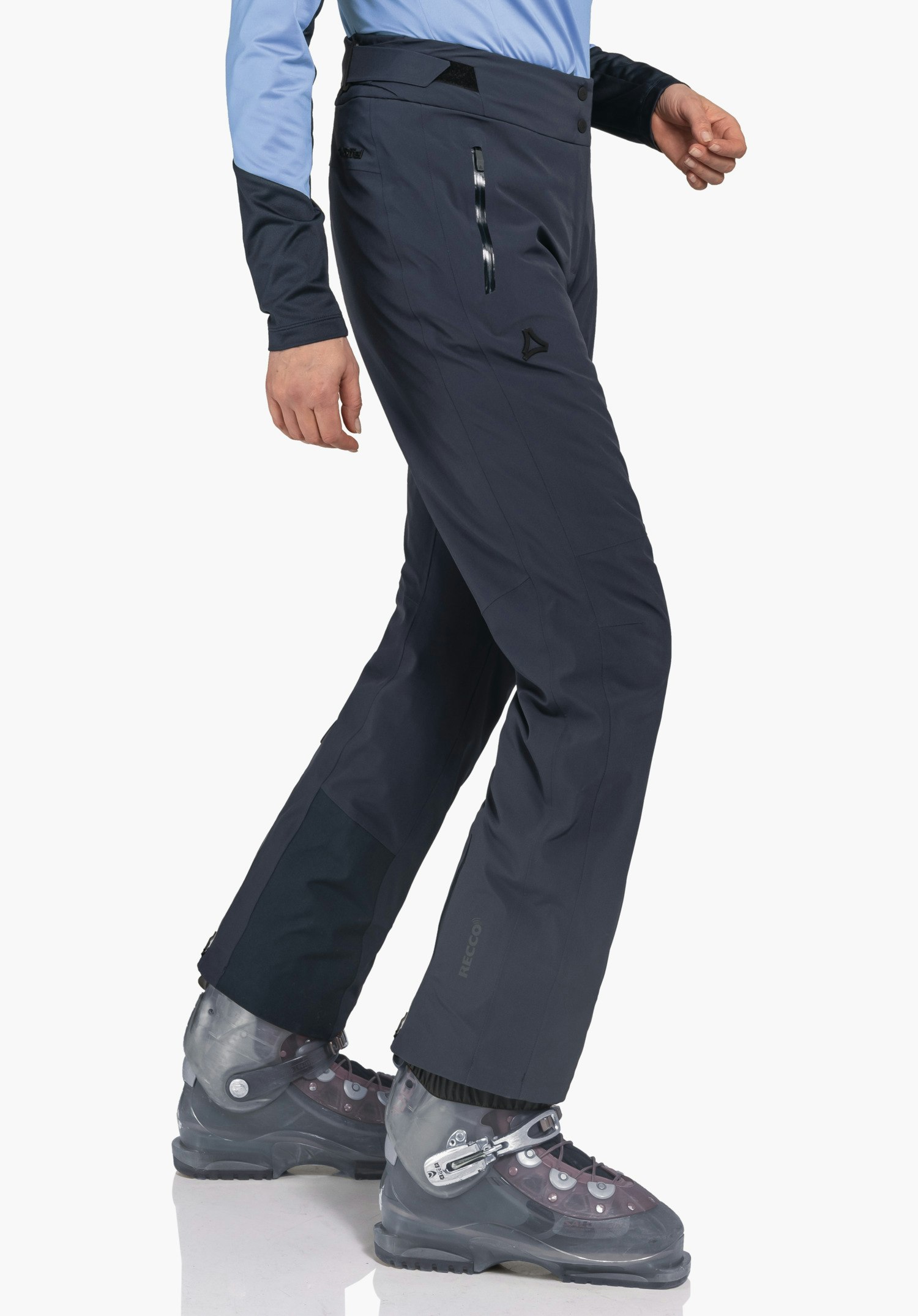 Pants Style Skayra WMS donkerblauwe broek met Schöffel-logo; persoon zet een stap en draagt een lichtblauw bovenstuk en zwarte skischoenen voor een witte studioachtergrond. Tekst: RECCO.