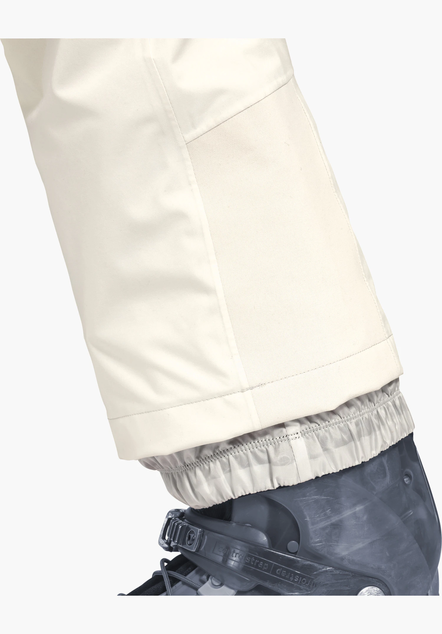 Pants Style Pine WMS toont de broekspijp in natur met robuuste randbescherming en elastische sneeuwvanger over de skischoen, close-up voor een witte/neutrale achtergrond.