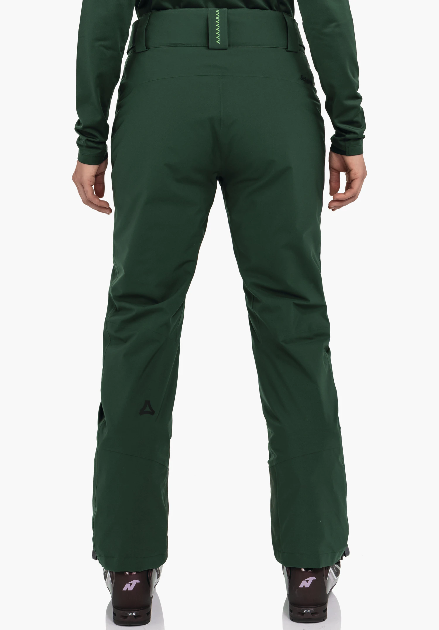 Pants Style Pine WMS donkergroene broek in achteraanzicht, gedragen door een staande persoon; gladde sportieve pasvorm, zwart Schöffel-logo op het linkeronderbeen, neutrale witte achtergrond. Tekst: "Schöffel", "26.5".