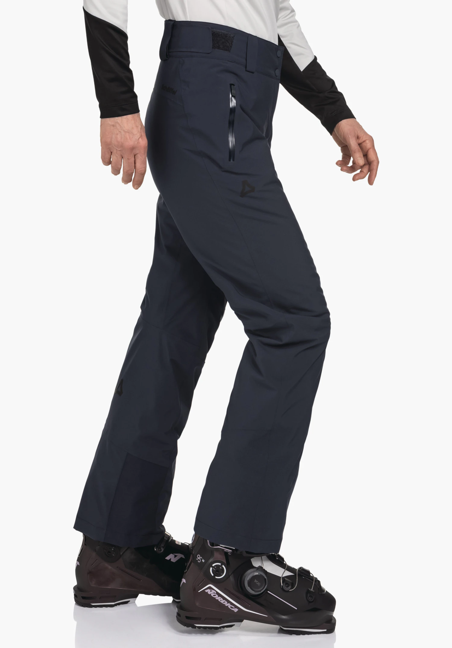 Pants Style Pine WMS donkerblauwe skibroek, gedragen door een persoon tijdens het lopen; Schöffel-logo op het bovenbeen; tekst "Schöffel" op de heup; zwarte skischoenen met tekst "NORDICA"; witte achtergrond.
