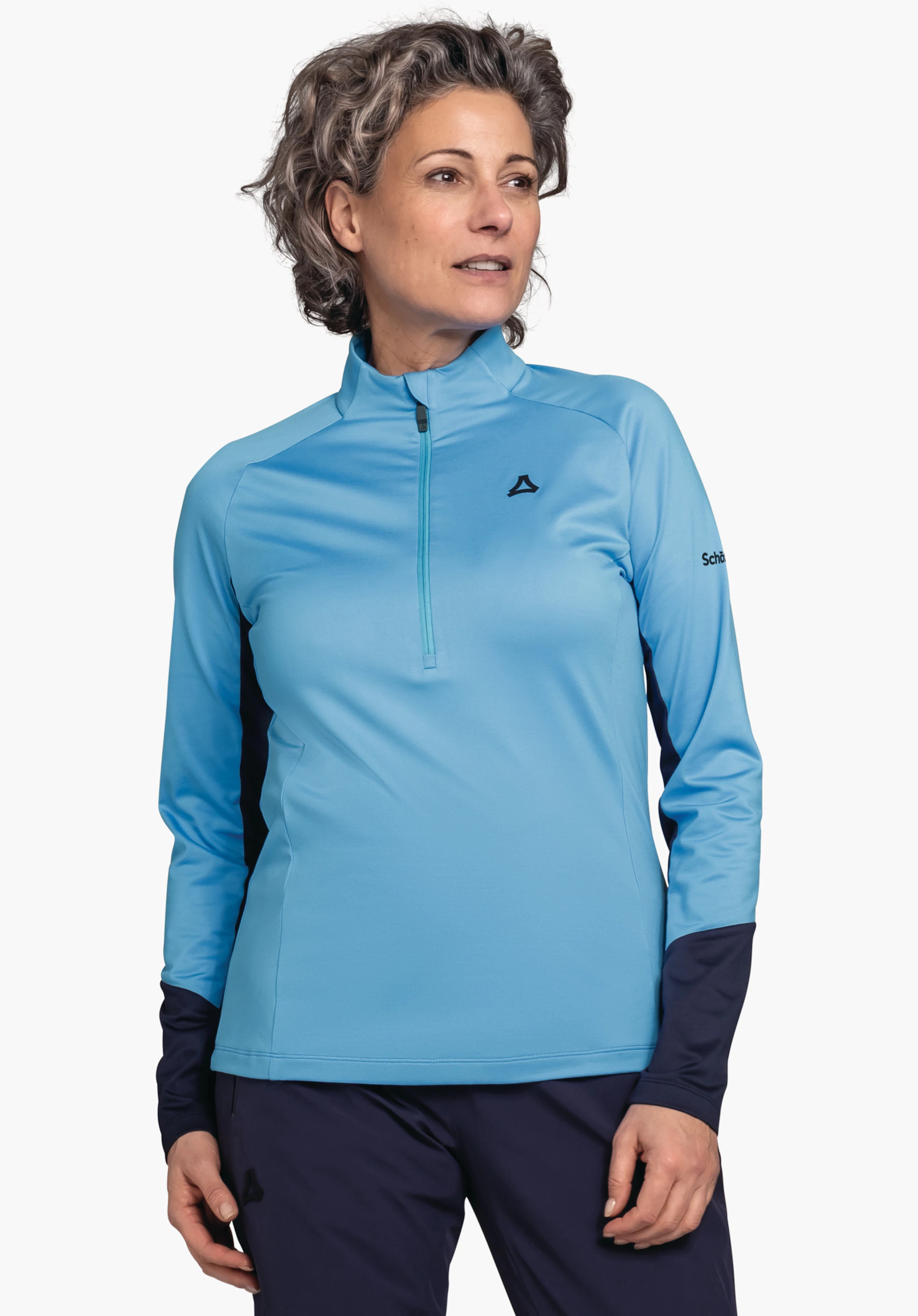 Longsleeve Style Safoon WMS lichtblauw longsleeve-shirt met halve ritssluiting en Schöffel-logo op de borst; persoon draagt het en kijkt zijwaarts; mouwen en broek donkerblauw; tekst op mouw: "Schöffel"; witte achtergrond.
