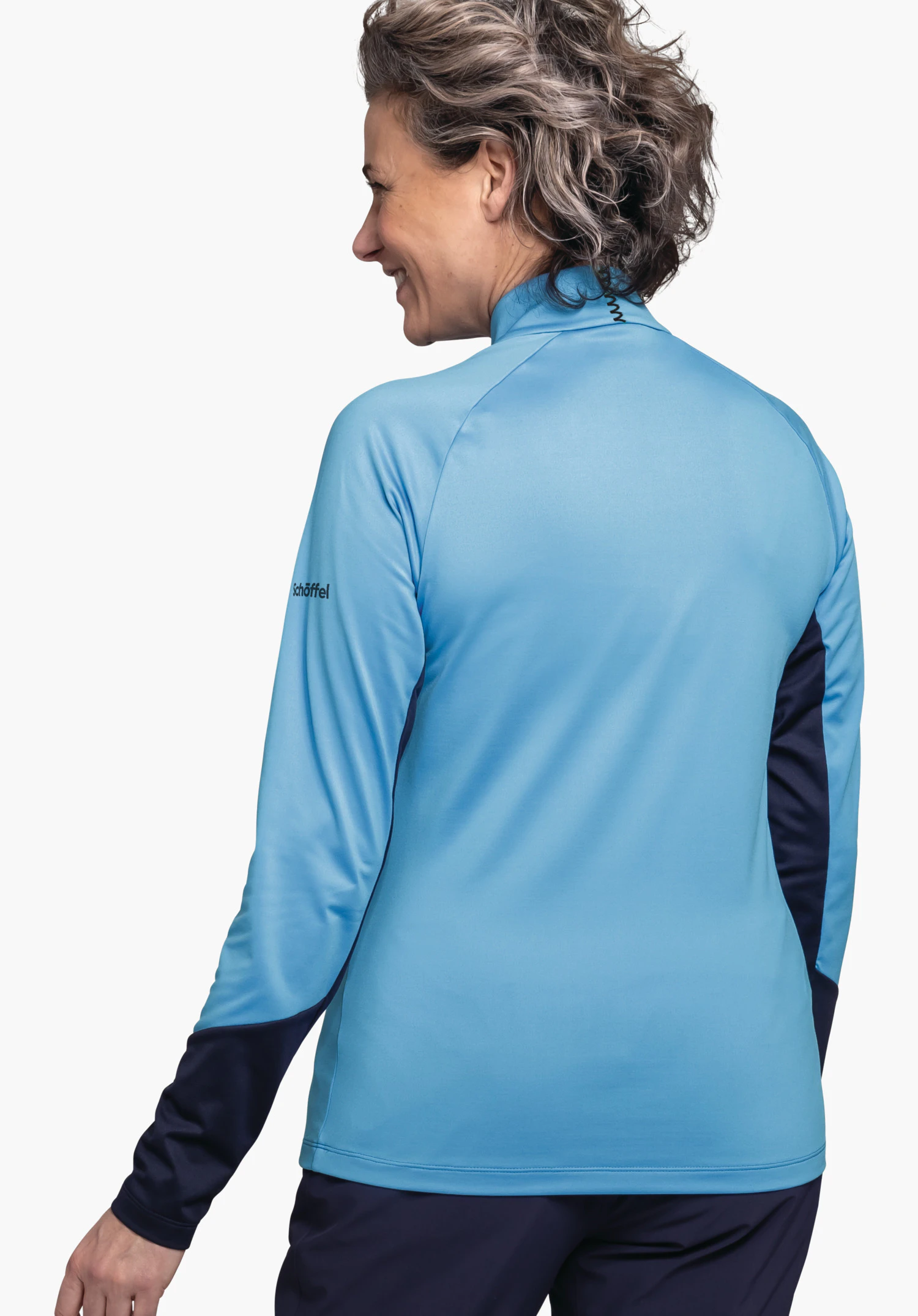 Longsleeve Style Safoon WMS lichtblauw langarmshirt met donkerblauwe inzetten, gedragen door een staande persoon die het hoofd naar links draait en glimlacht; witte studioachtergrond. Tekst: "schöffel".