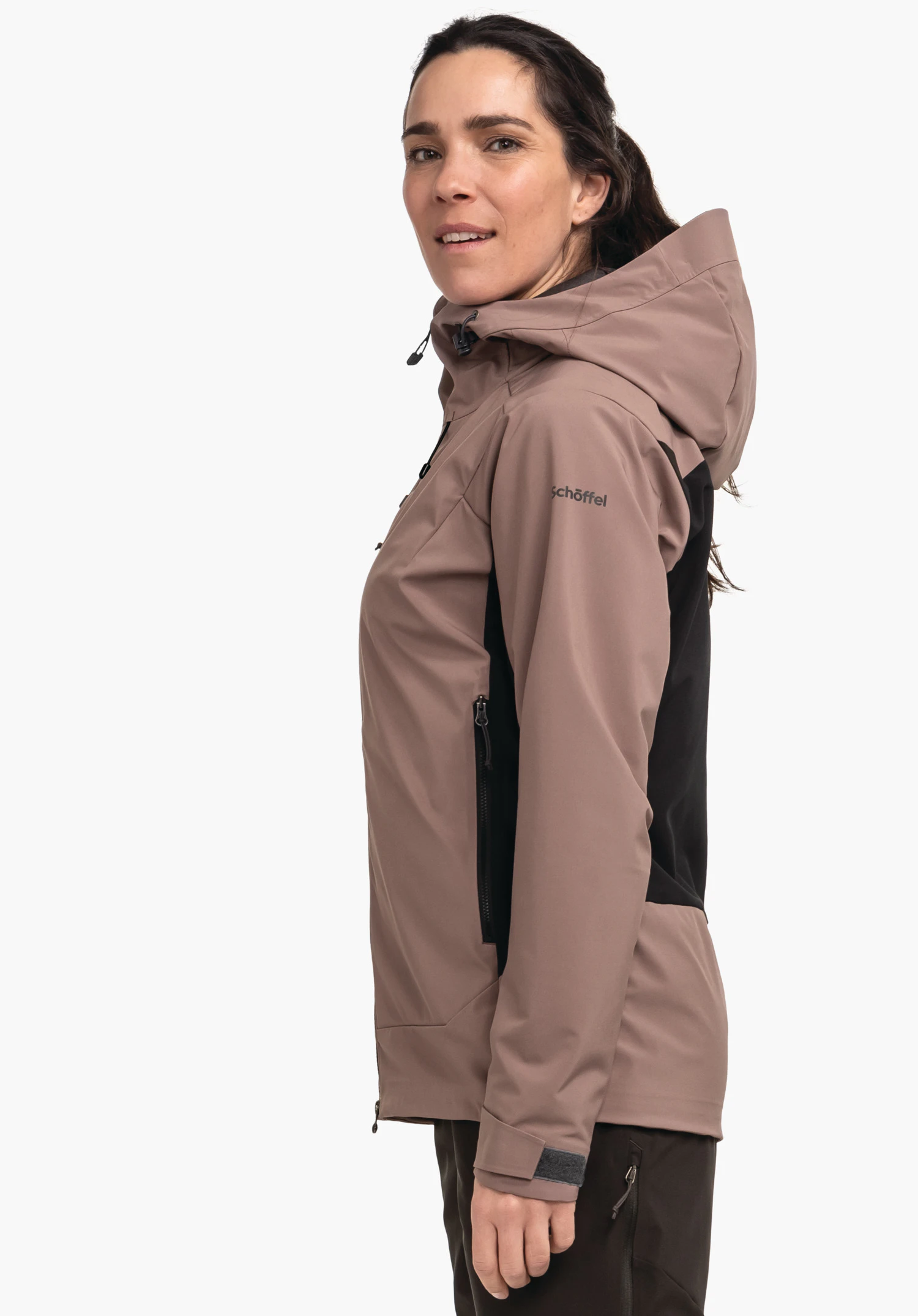 Softshell Jk Style Milagle WMS veste — femme la porte, debout de profil et regardant légèrement la caméra; veste à capuche rouge foncé avec empiècement latéral noir devant fond blanc. Texte: "Schöffel".