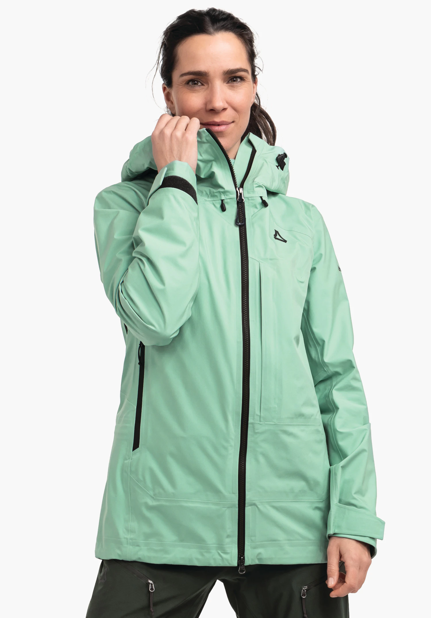 Jacket Style Milagle WMS light green outdoor jacket; woman pulls the zip up at the collar, Schöffel logo on the chest, black zips and details, hood; standing shot against a white background.