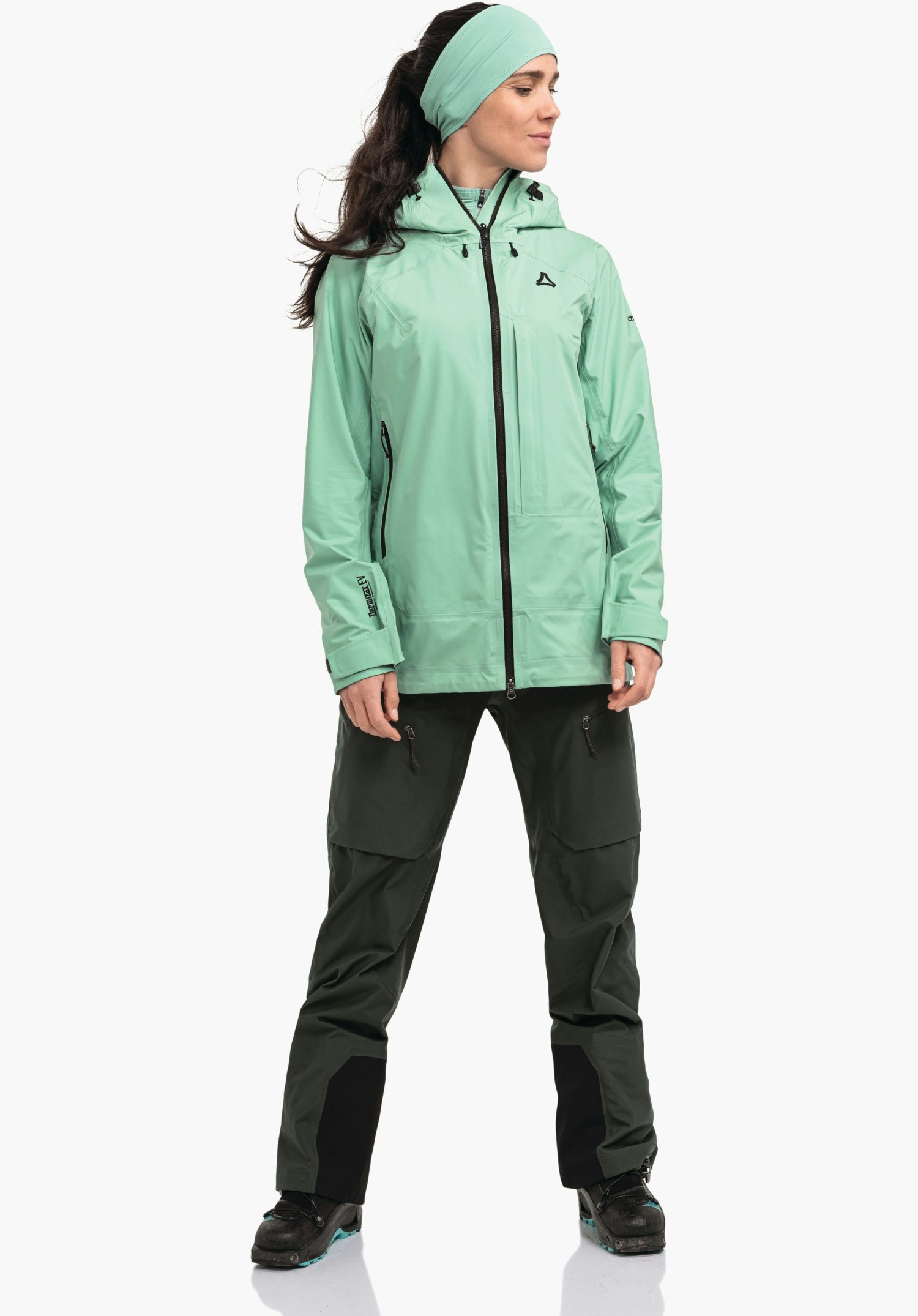 Jacket Style Milagle WMS shows the black Schöffel logo on the left chest, surrounded by the smooth green technical fabric and the central front zip, close-up shot against a white/neutral background.