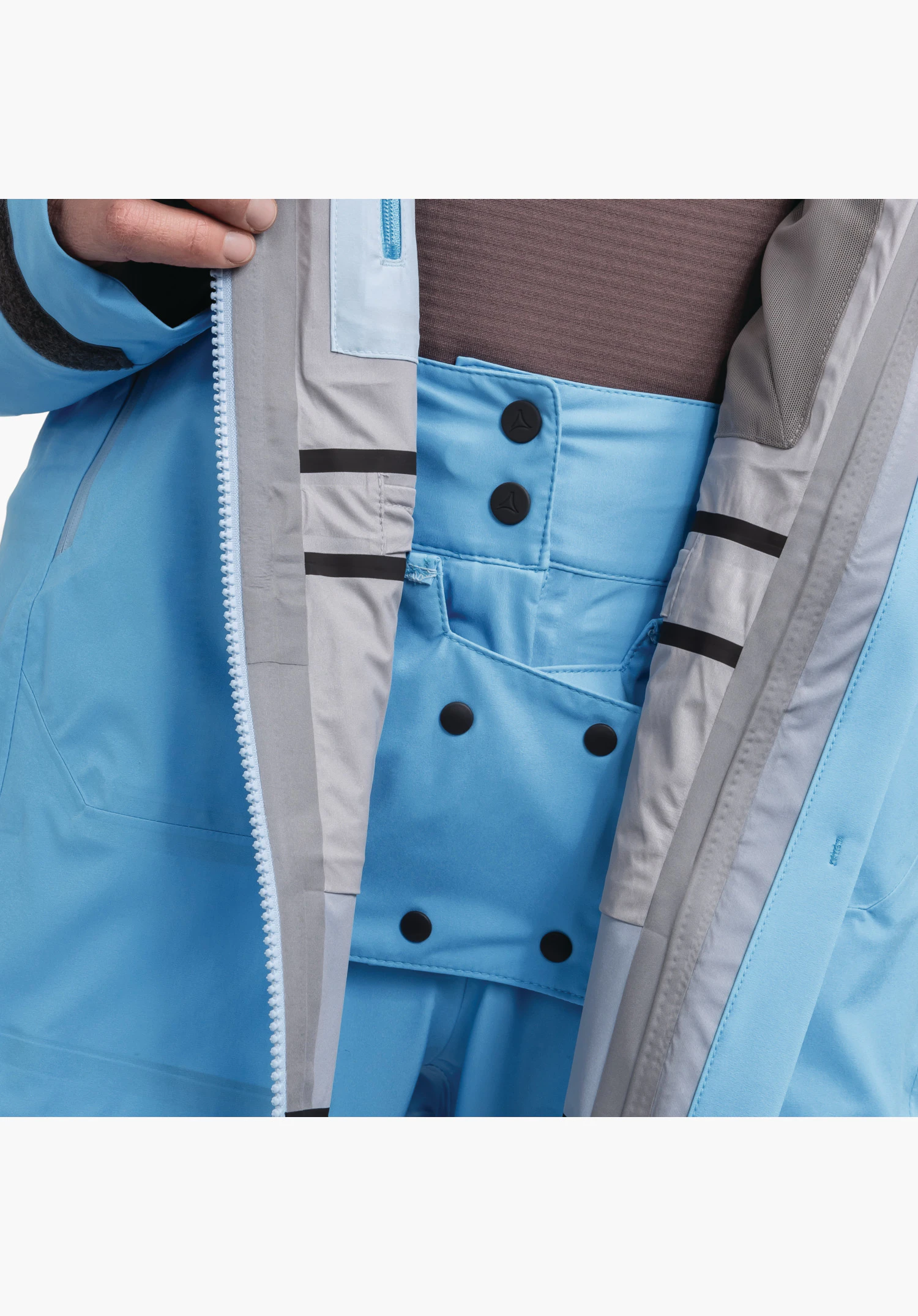 Jacket Style Milagle WMS zeigt den integrierten, blauen Schneefang mit Druckknopf-Verbindungssystem zur Hose als Nahaufnahme vor weißem Hintergrund.